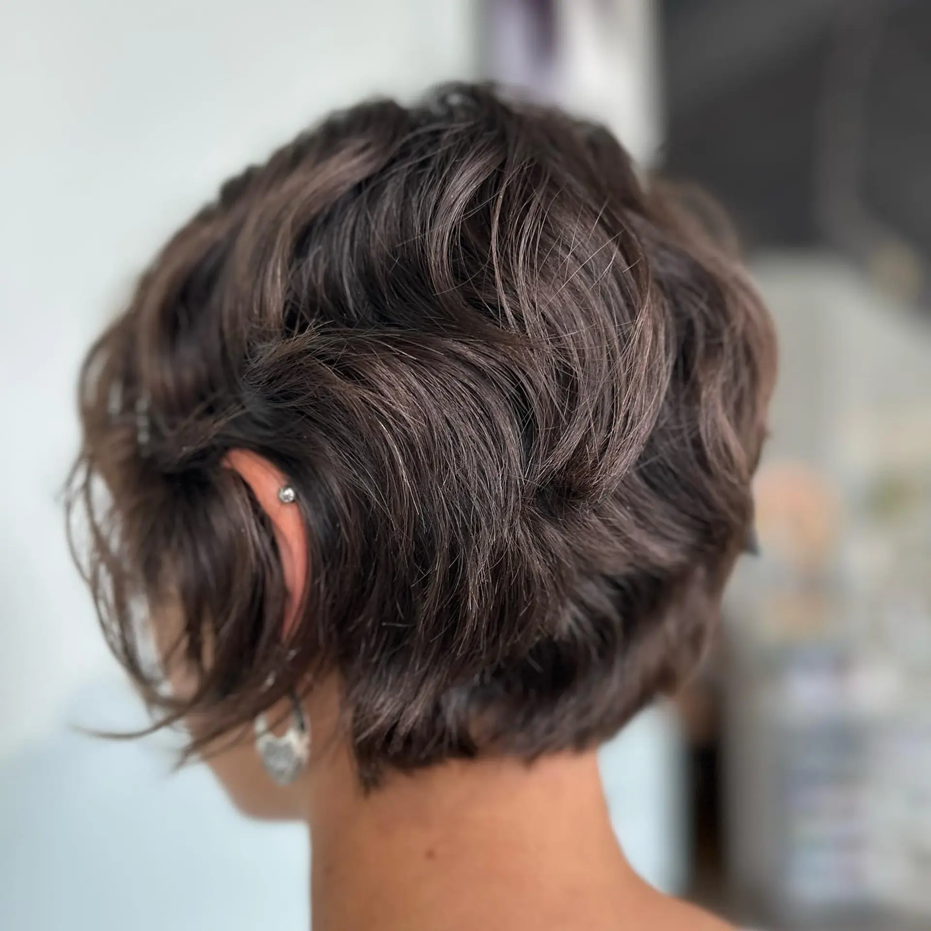 A textured bixie haircut styled with soft, piecey waves and volume around the crown. 1