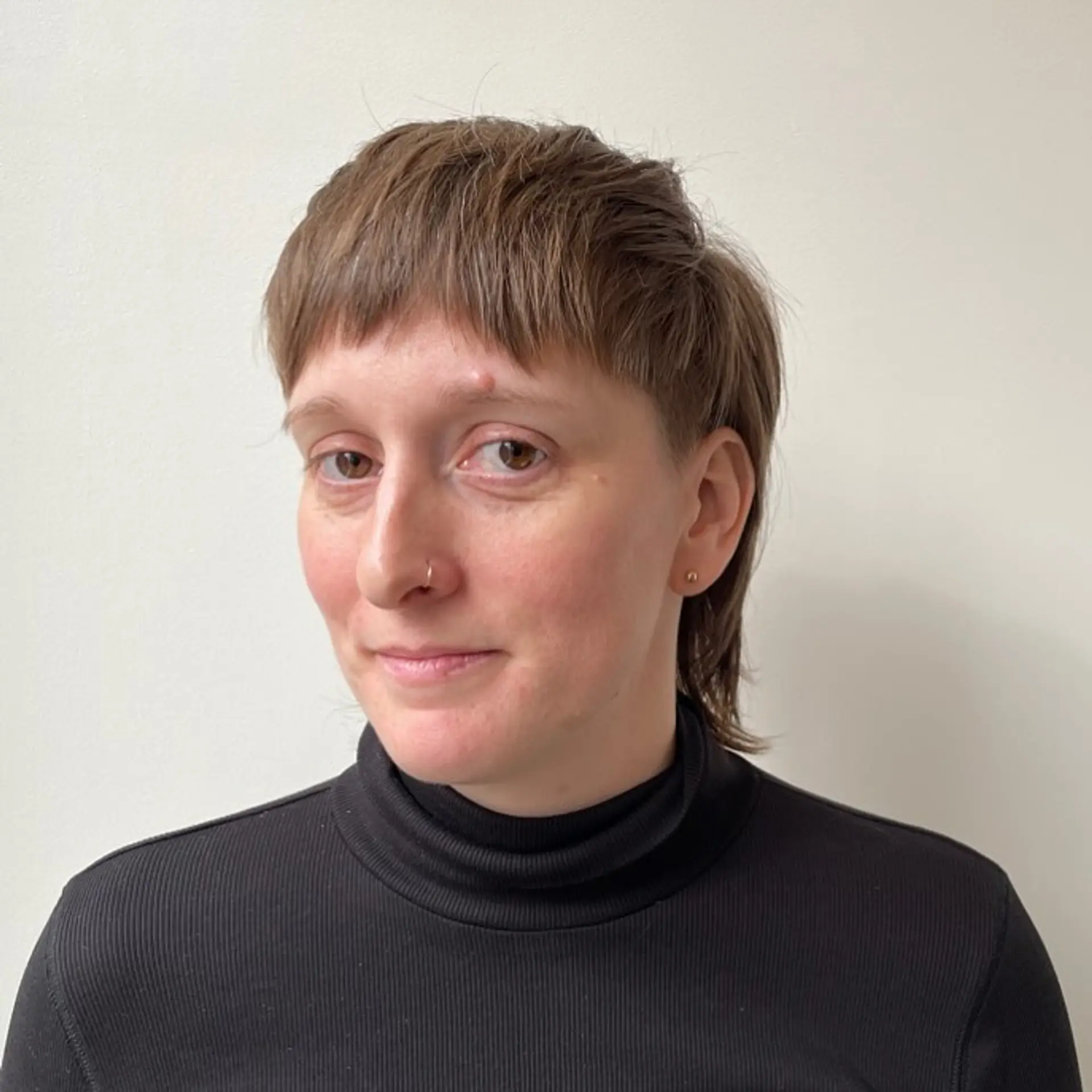 Short, straight brown hair styled in a modern mullet with textured top, layered back, fringe bangs, and tapered sides. 1