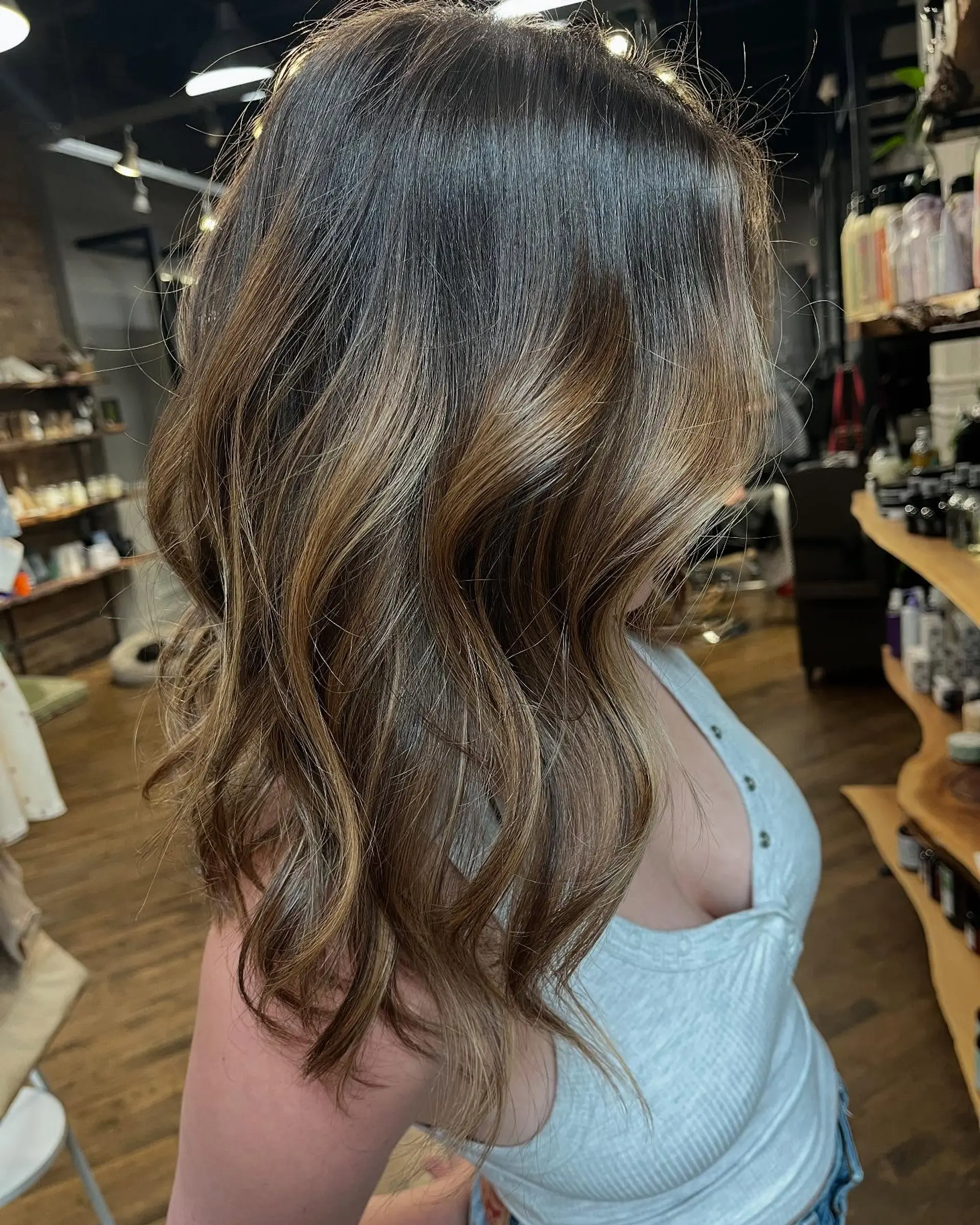 Medium-length brunette hair featuring a seamless caramel balayage styled with soft, relaxed waves. 1