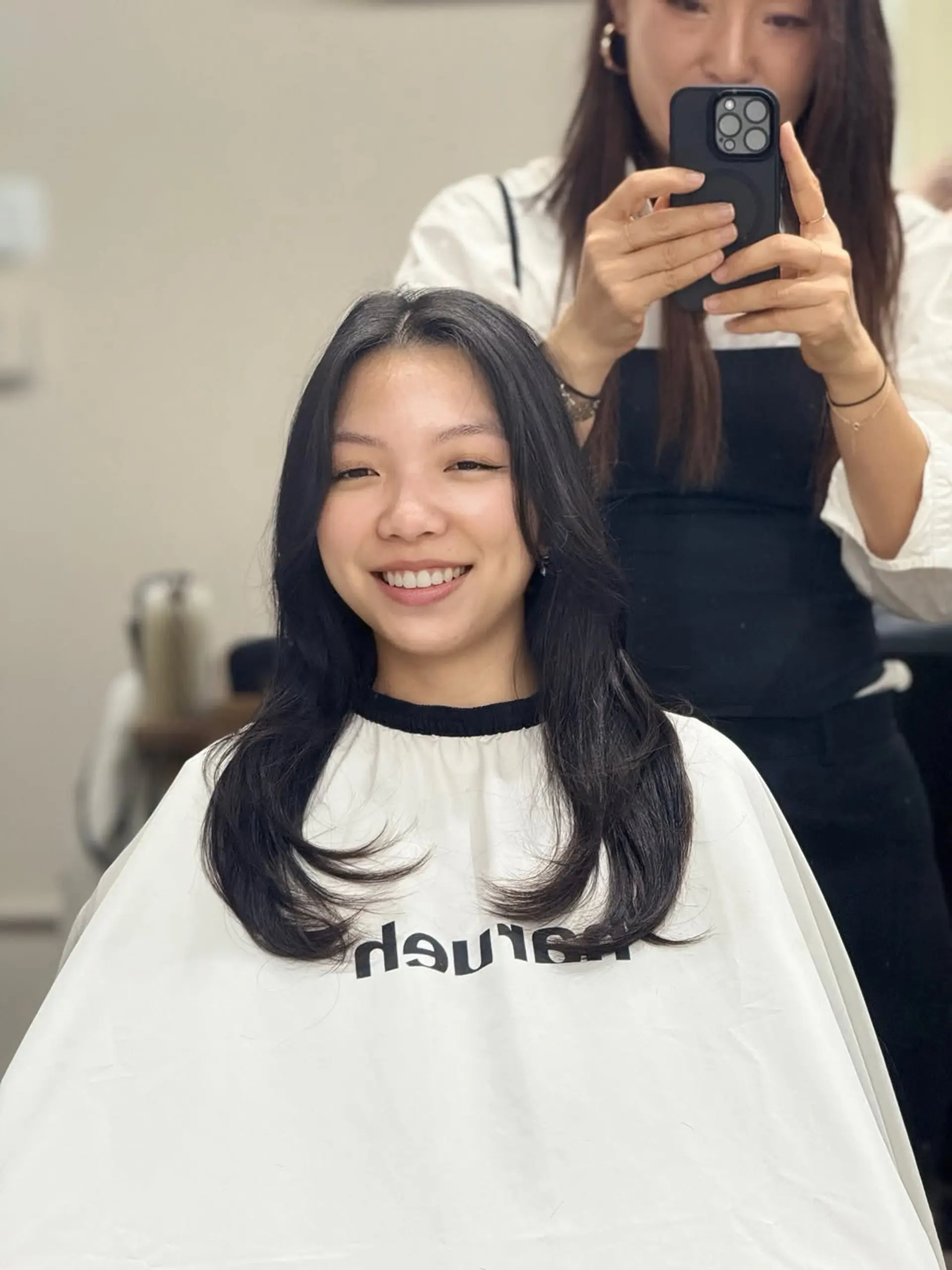 A sophisticated long-layered cut with face-framing elements and soft, rounded volume at the tips, styled with a classic center part. 1