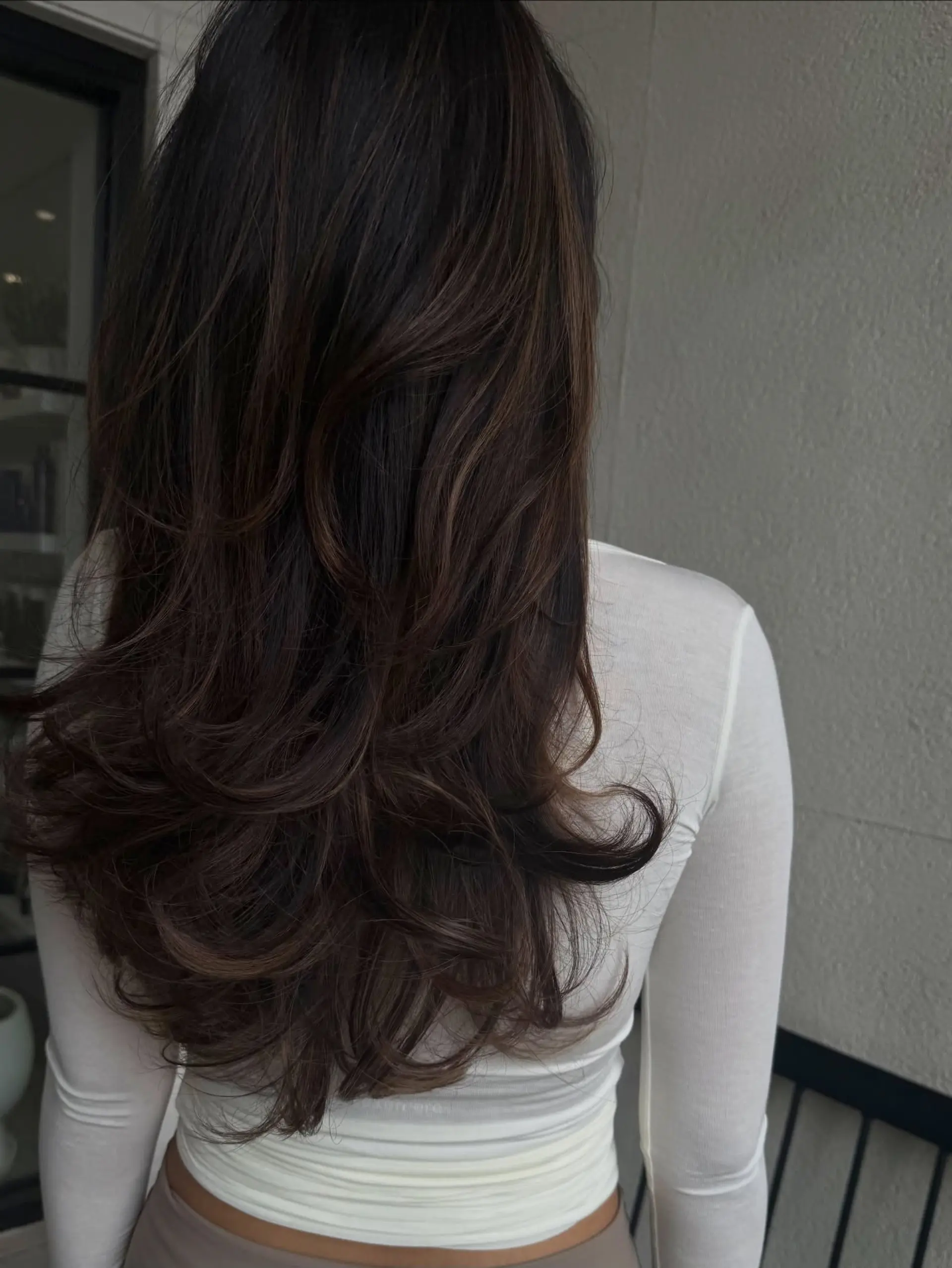 Long, layered dark chocolate brown hair styled into a bouncy blowout with voluminous flipped ends. 1