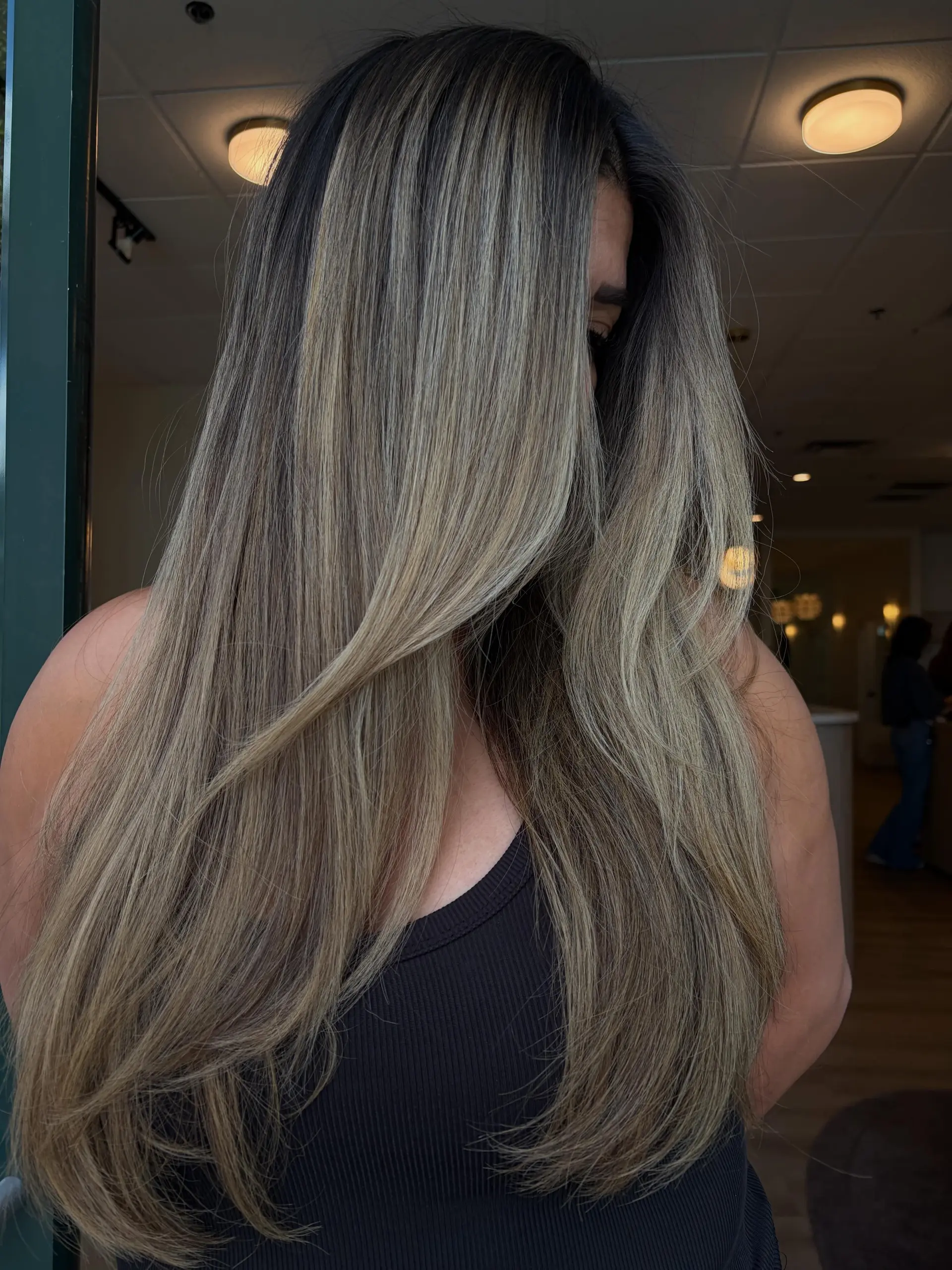 Extra long, sleek hair showcasing finely blended cool-toned ash blonde highlights over a dark brunette base. 1