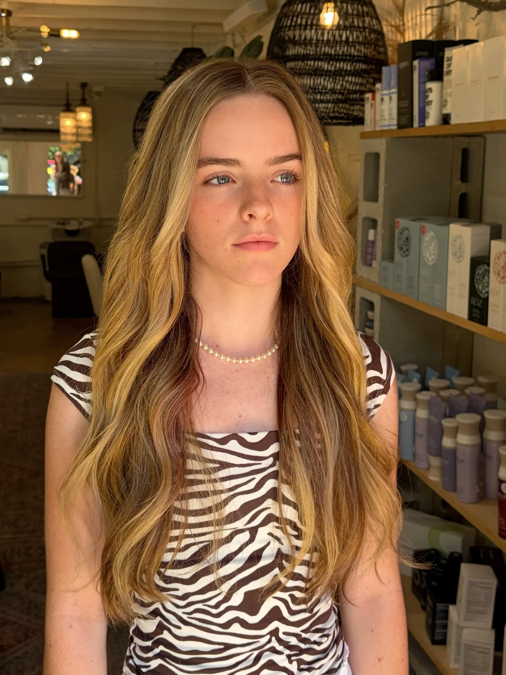 Long wavy hair enhanced with multi-dimensional warm blonde highlights and brighter face-framing strands. 1