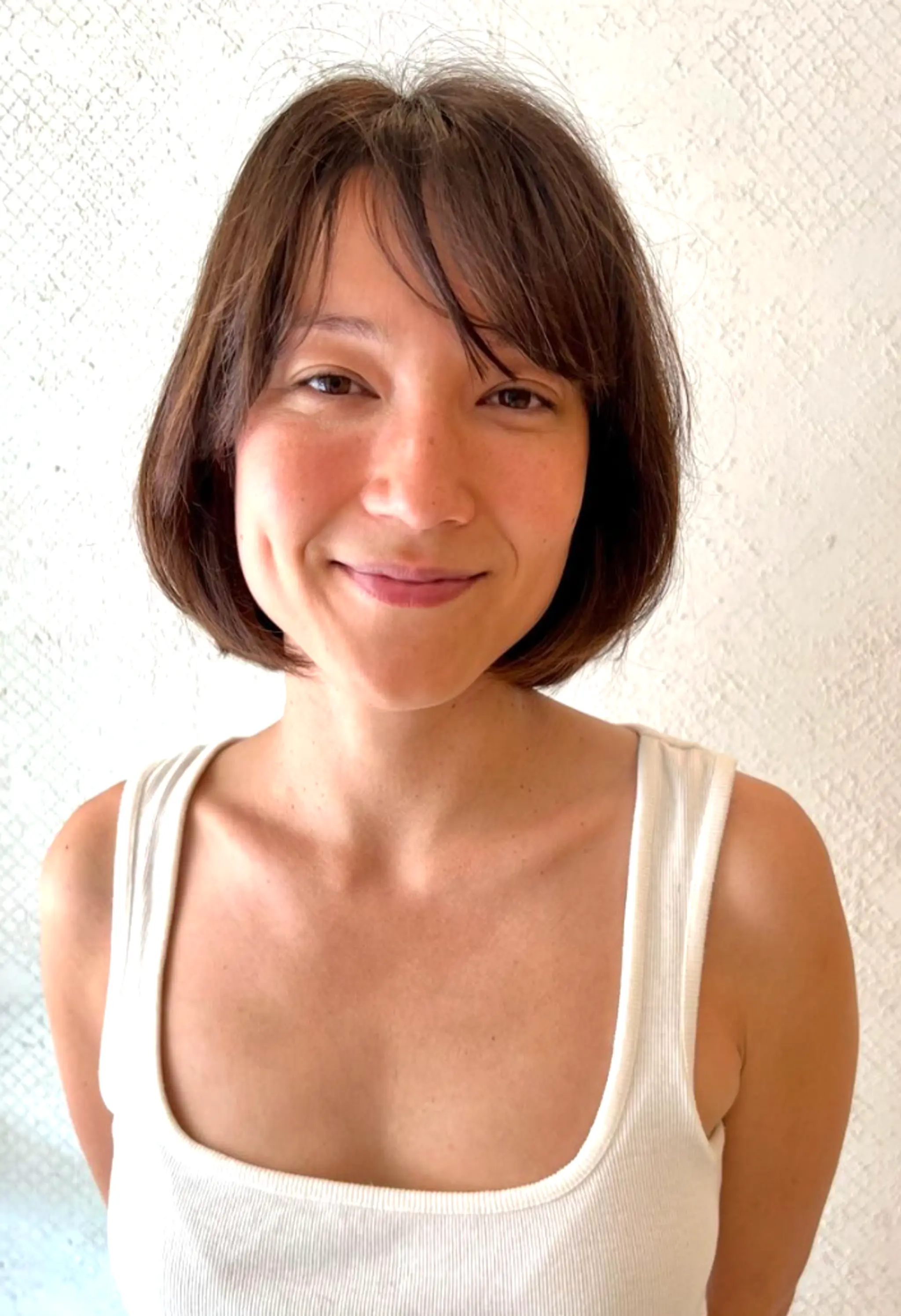 The chic bob features a short, straight cut with subtle waves and a soft fringe. Dark brown hair falls just below the chin with face-framing layers, adding depth and effortless style. 1