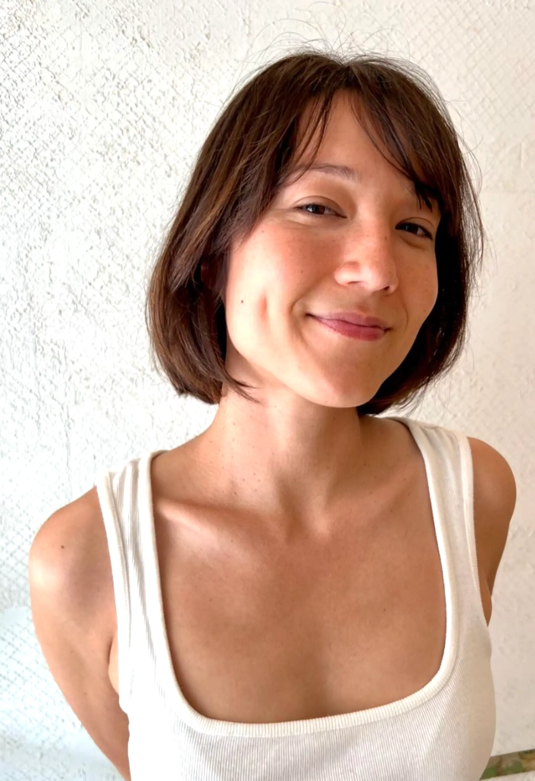 The chic bob features a short, straight cut with subtle waves and a soft fringe. Dark brown hair falls just below the chin with face-framing layers, adding depth and effortless style. 2