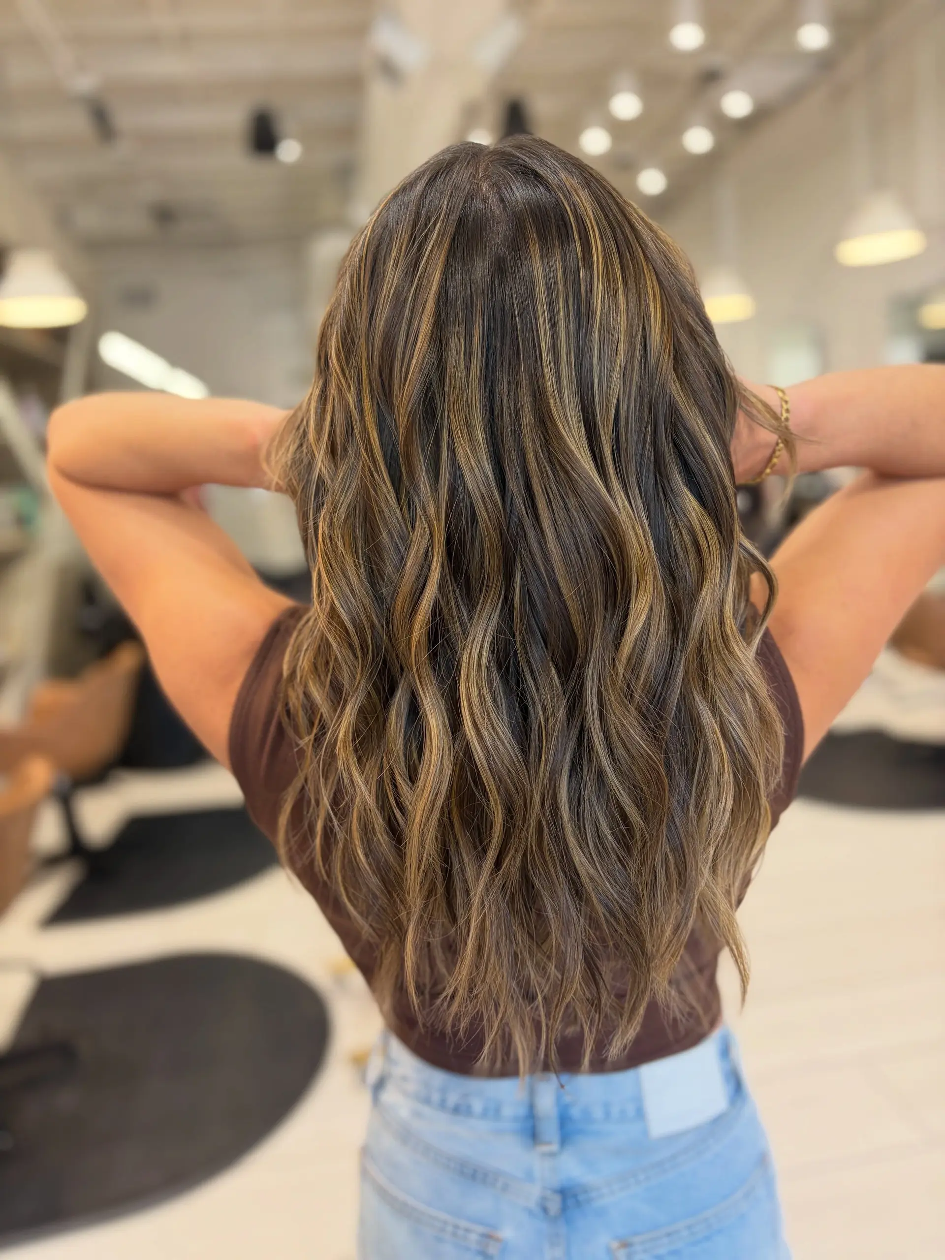 Long wavy brunette hair detailed with soft, lived-in warm caramel highlights. 1