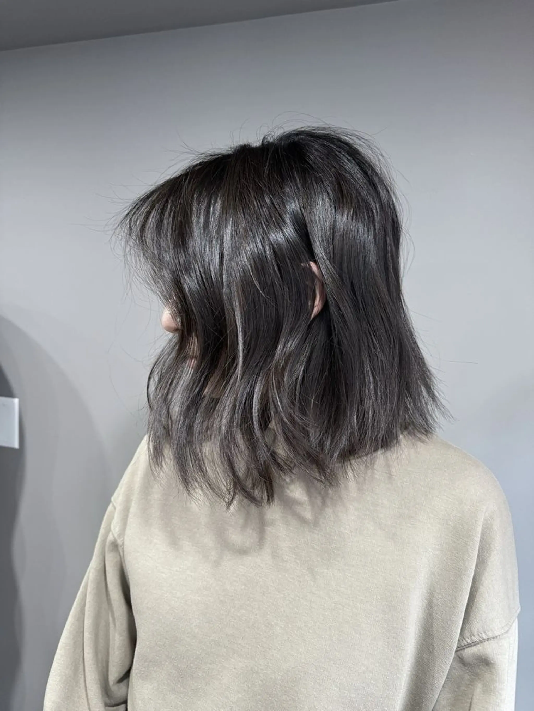 A medium-length, dark brown hairstyle featuring textured, wavy layers that create a chic, modern shag appearance.