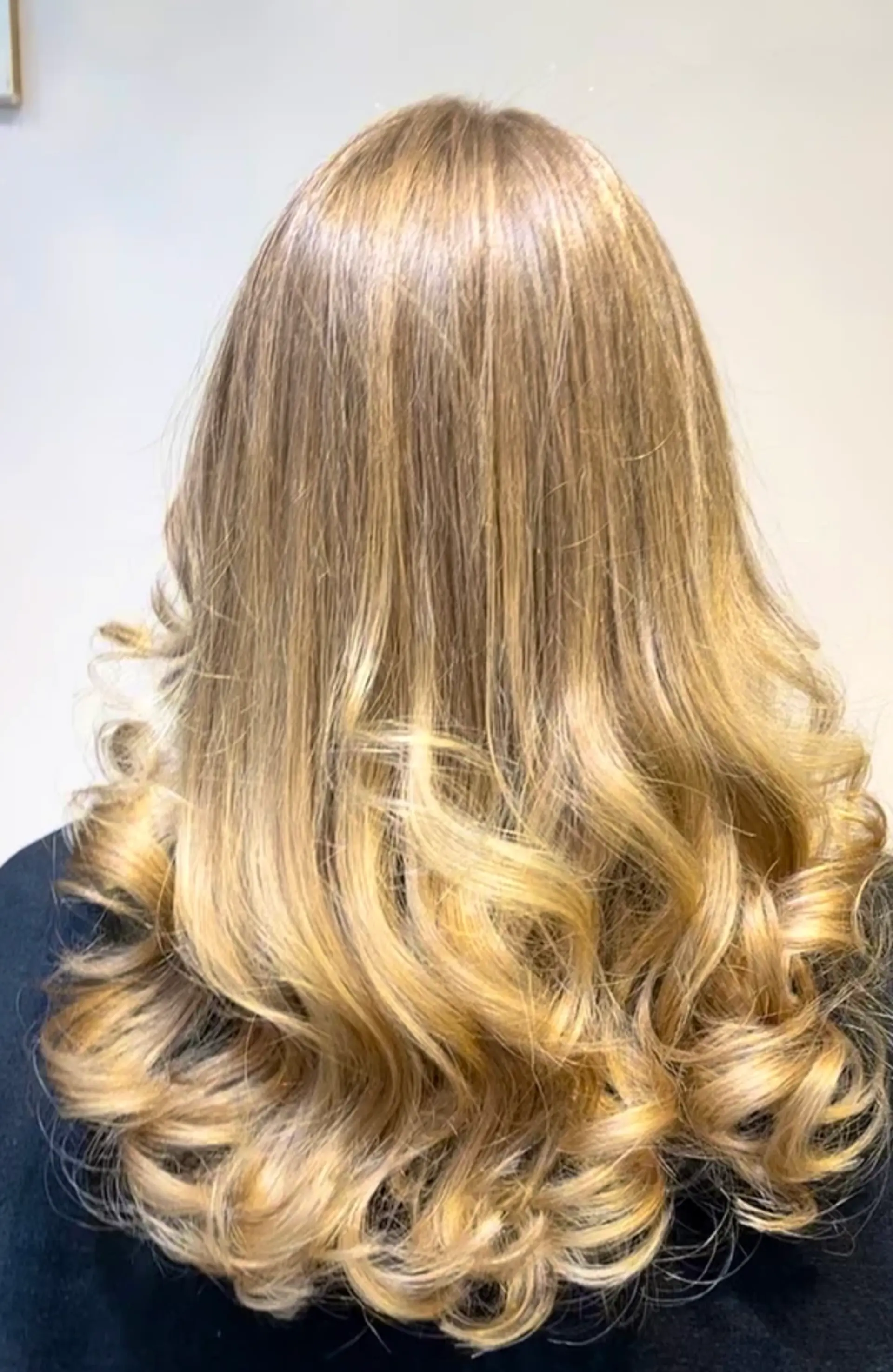 Long, golden blonde wavy hair with a glossy finish and voluminous, cascading ends accentuated by subtle highlights. 1