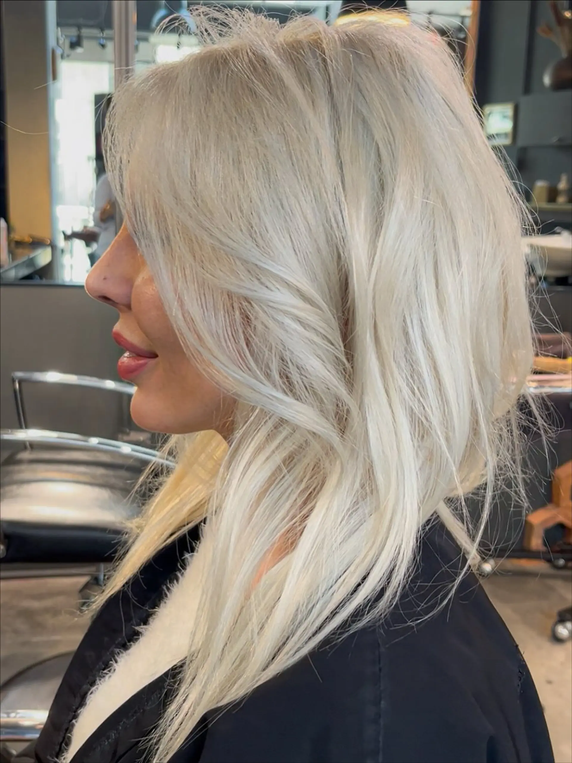 Bright, cool-toned platinum blonde hair cut into medium-length layers with face-framing sweep and soft blowout styling. 1