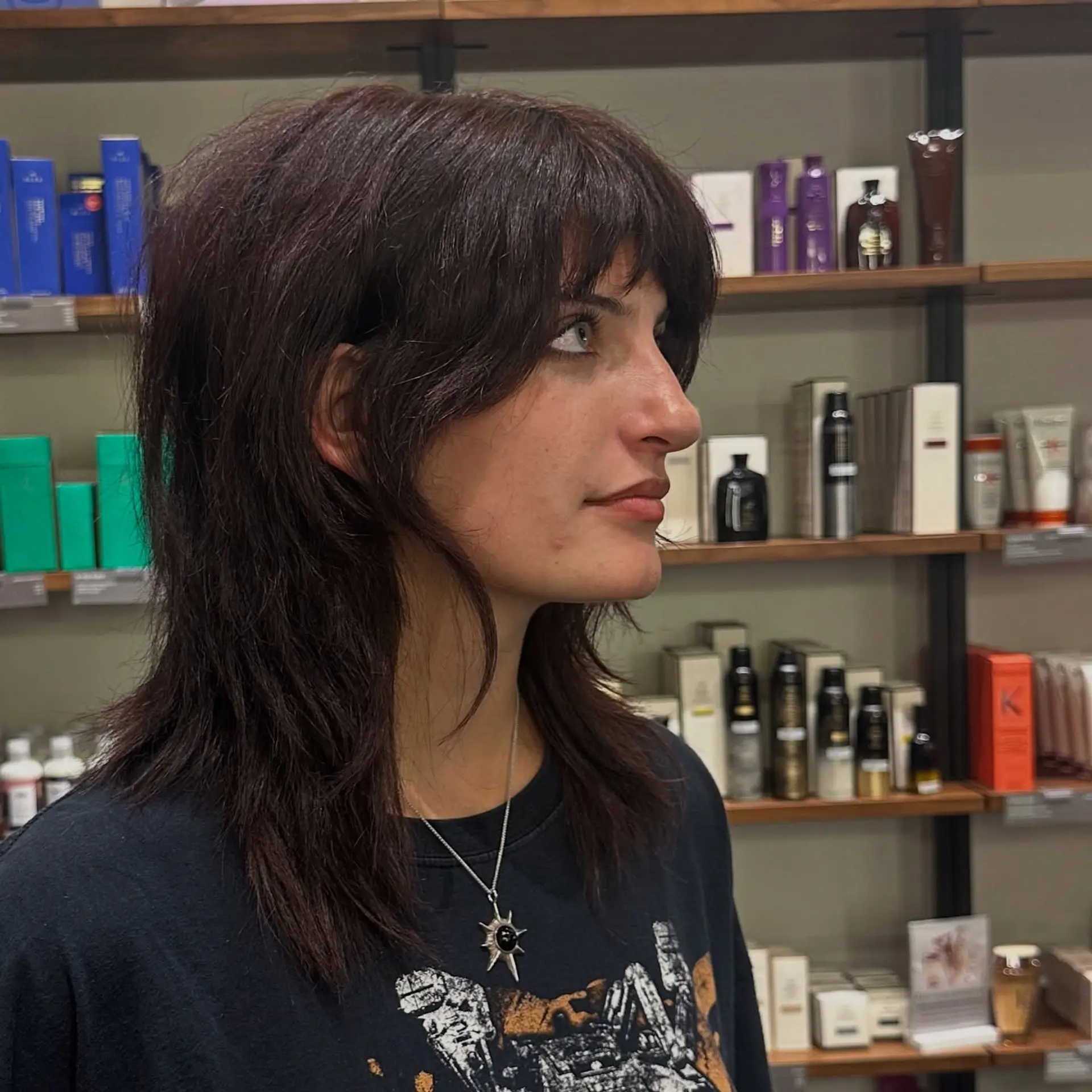 A choppy, heavily layered wolf cut featuring a full textured fringe and blended face-framing pieces that taper smoothly into collarbone-length ends. 1
