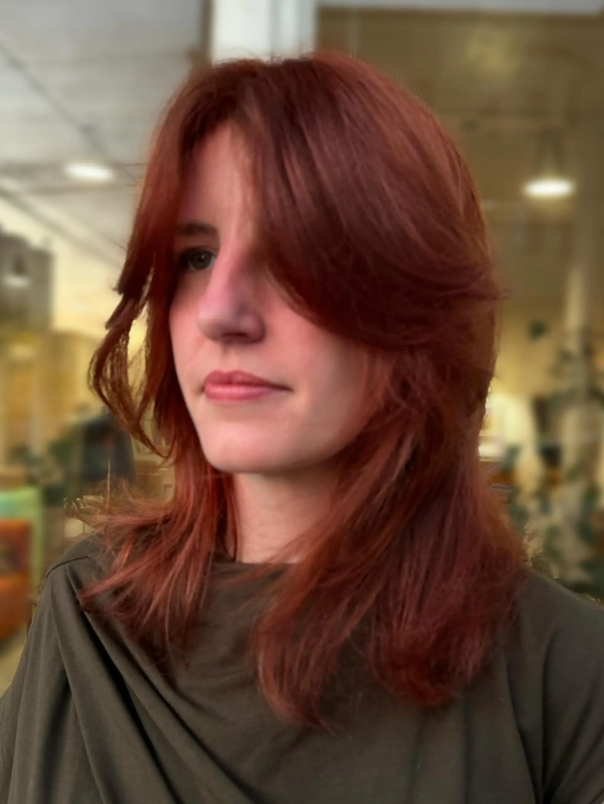 Medium-length red hair cut into soft layers with face-framing curtain bangs. 1