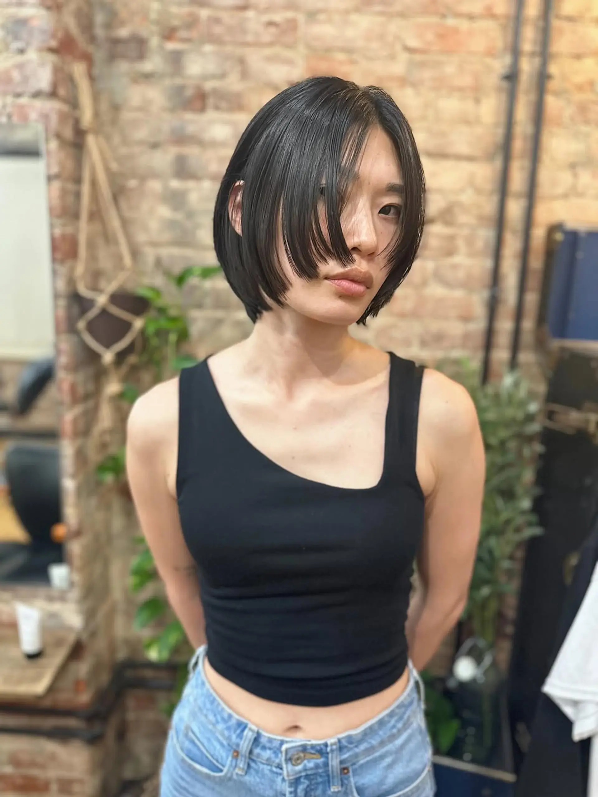 A chic, short blunt bob cut ending around the chin, paired with a heavy, full fringe that frames the face and covers the forehead, creating a sharp and stylish look with clean lines. 1