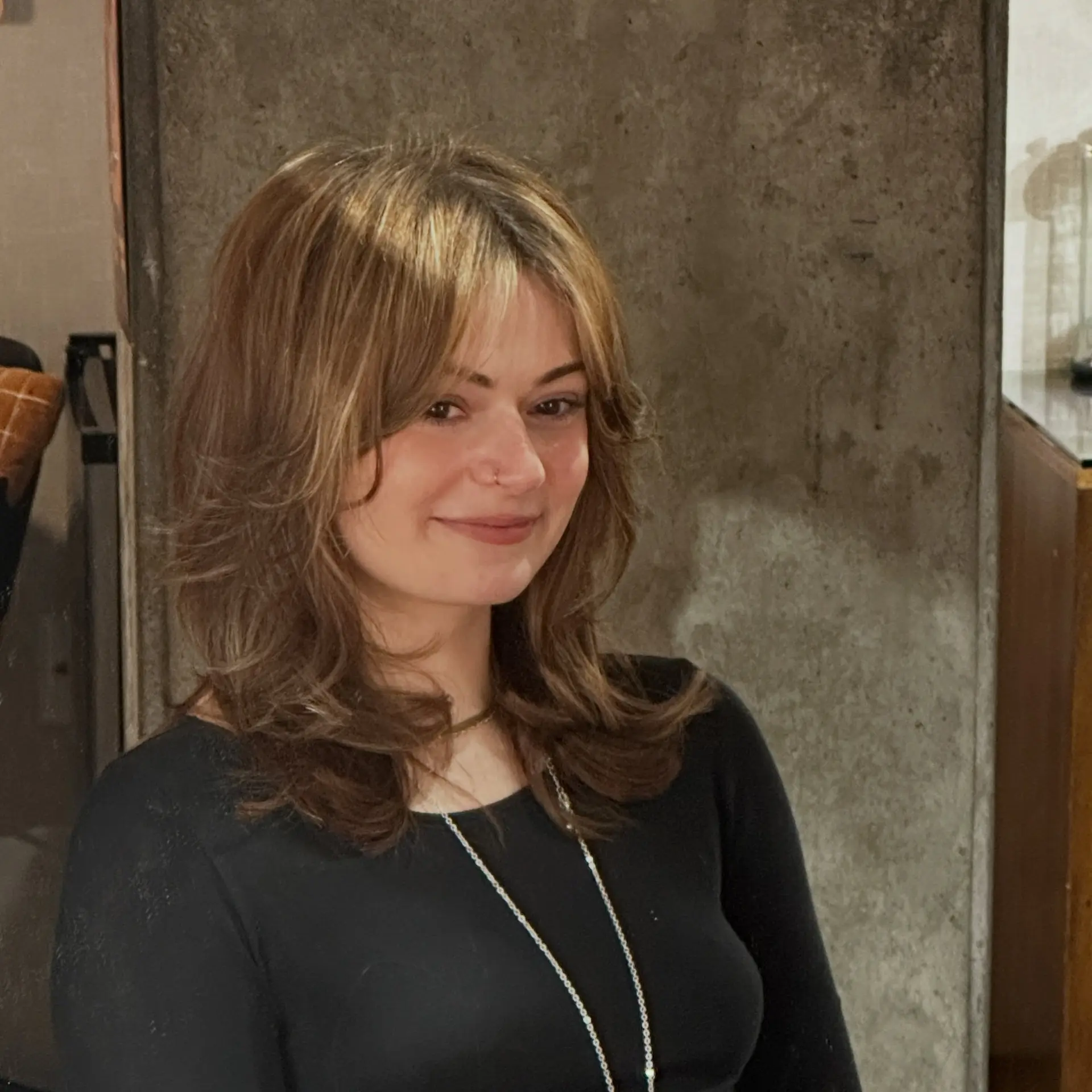 A 90s-inspired medium layered cut featuring voluminous crown layers, flicked-out ends at the collarbone, and feathered face-framing curtain fringe. 1
