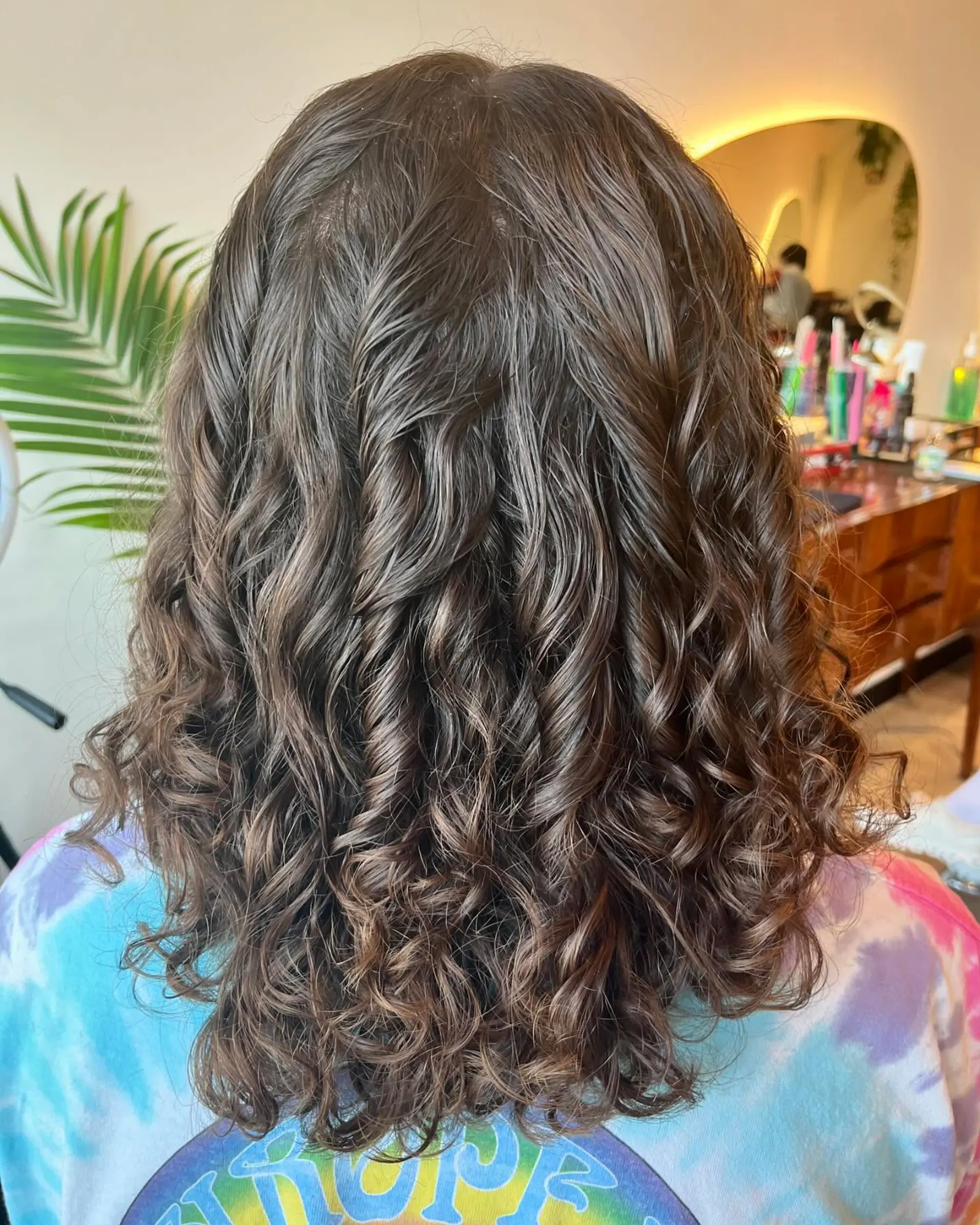 Shoulder-length natural brown curls styled with definition and gentle bounce. 1