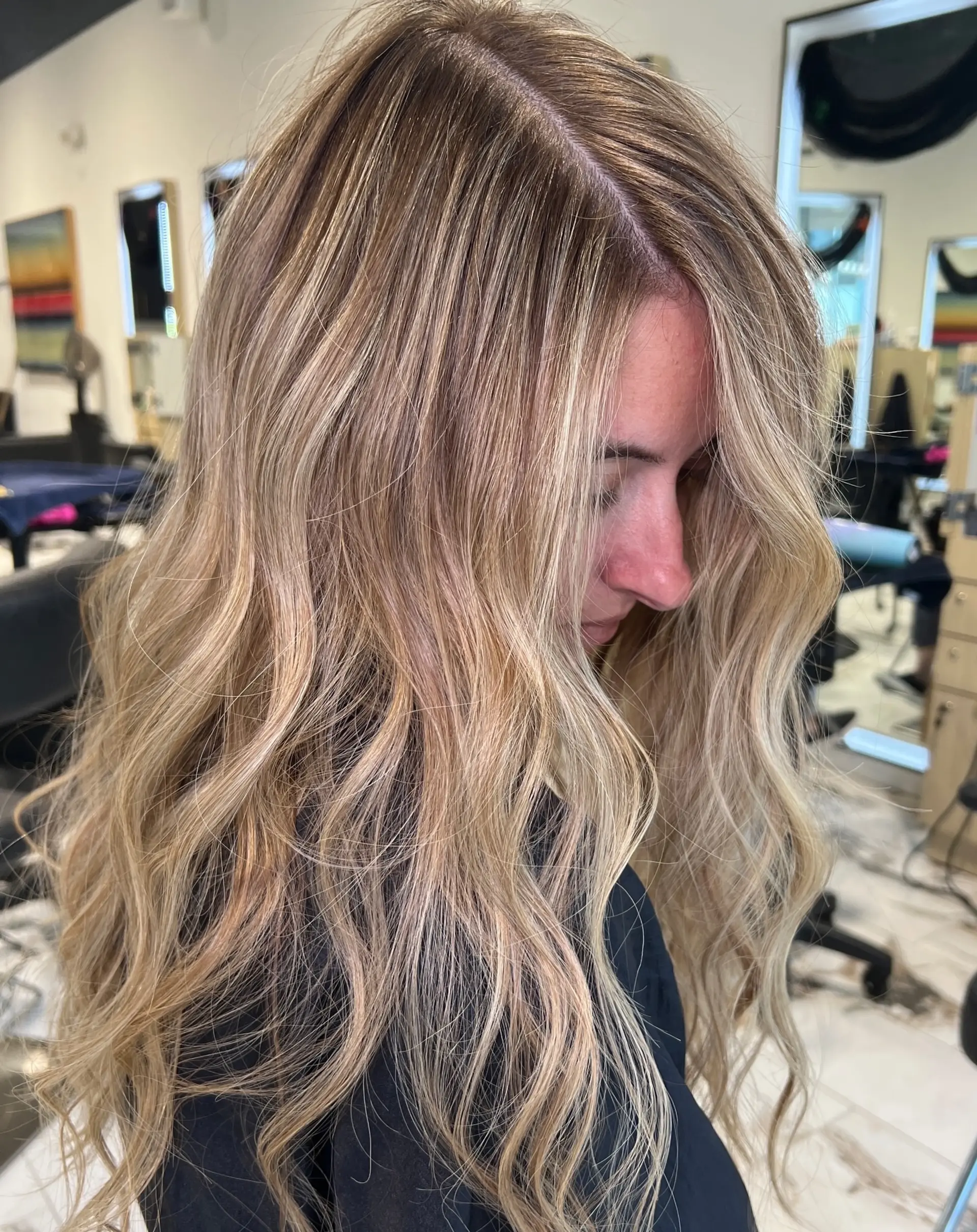 Long hair styled with soft, loose waves featuring dimensional multi-tonal blonde highlights and lowlights. 1