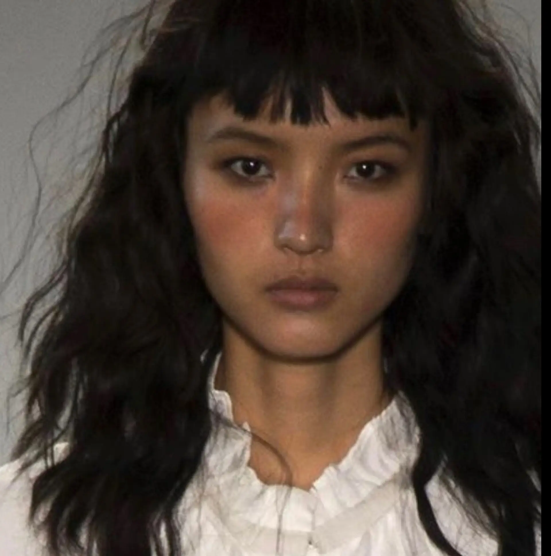 Medium-length dark wavy hair featuring choppy micro bangs and textured, layered waves. 1