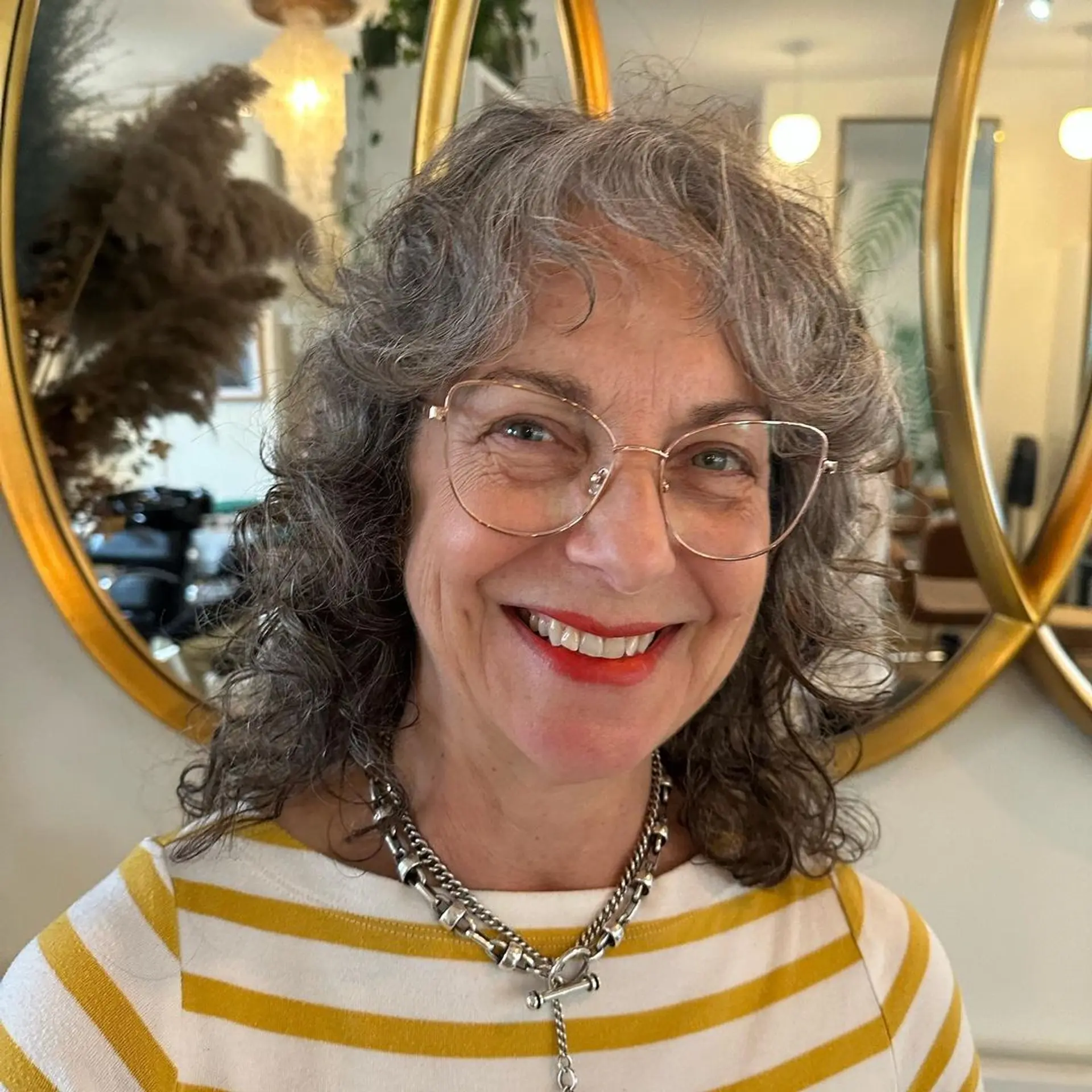 Naturally curly, medium-length gray hair styled in cascading layers with face-framing curls. 1