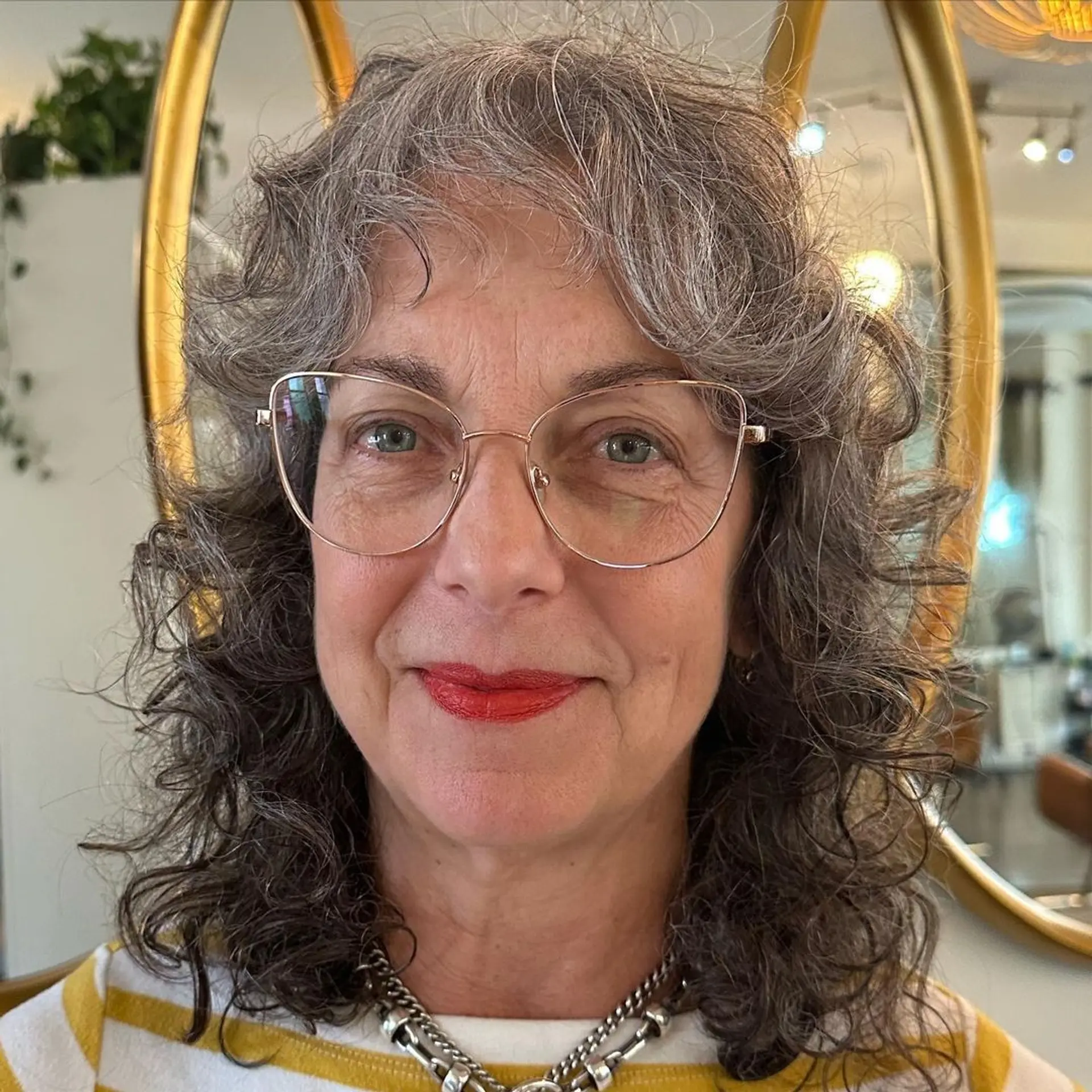 Naturally curly, medium-length gray hair styled in cascading layers with face-framing curls. 2