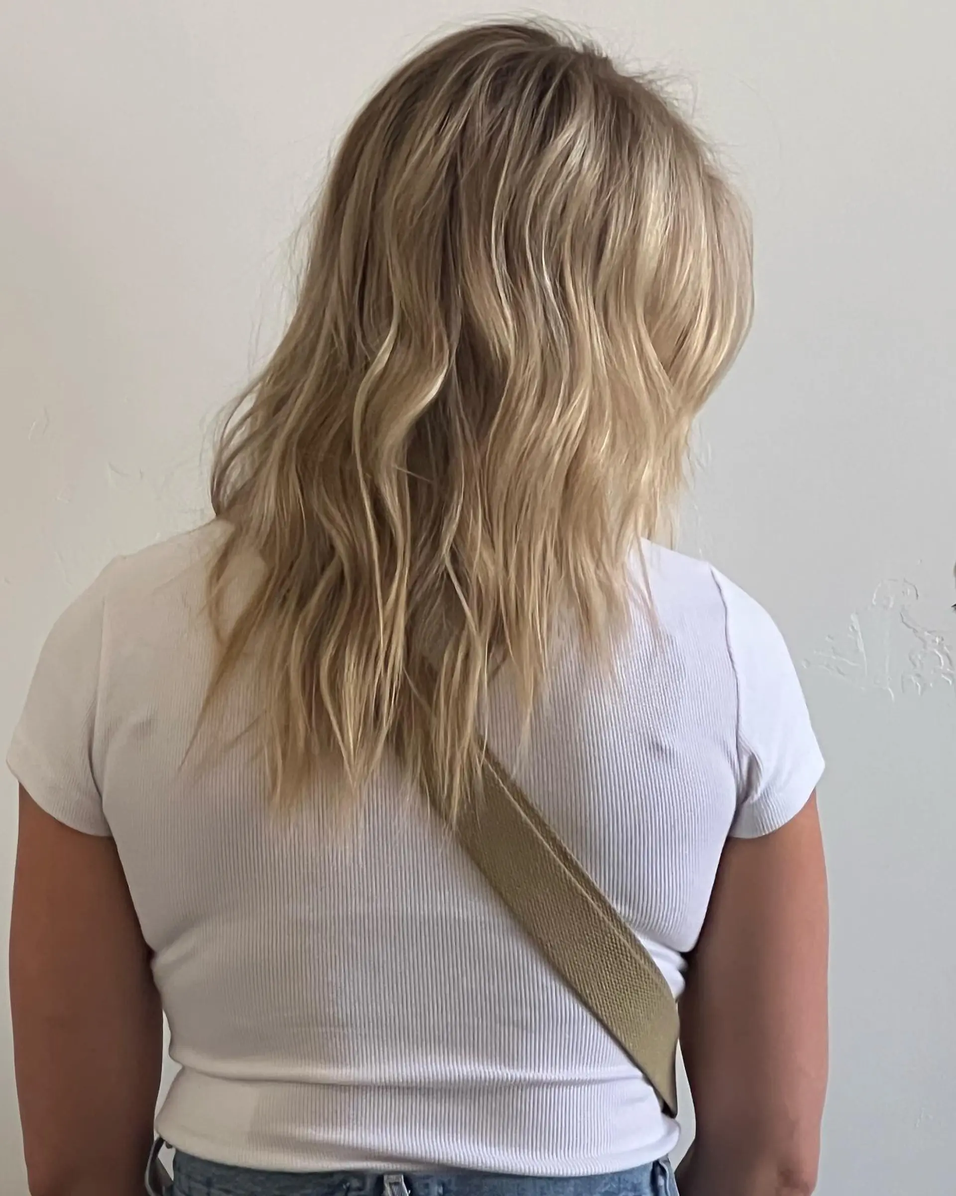 Mid-length dimensional blonde hair with soft, textured beach waves and feathered ends. 1
