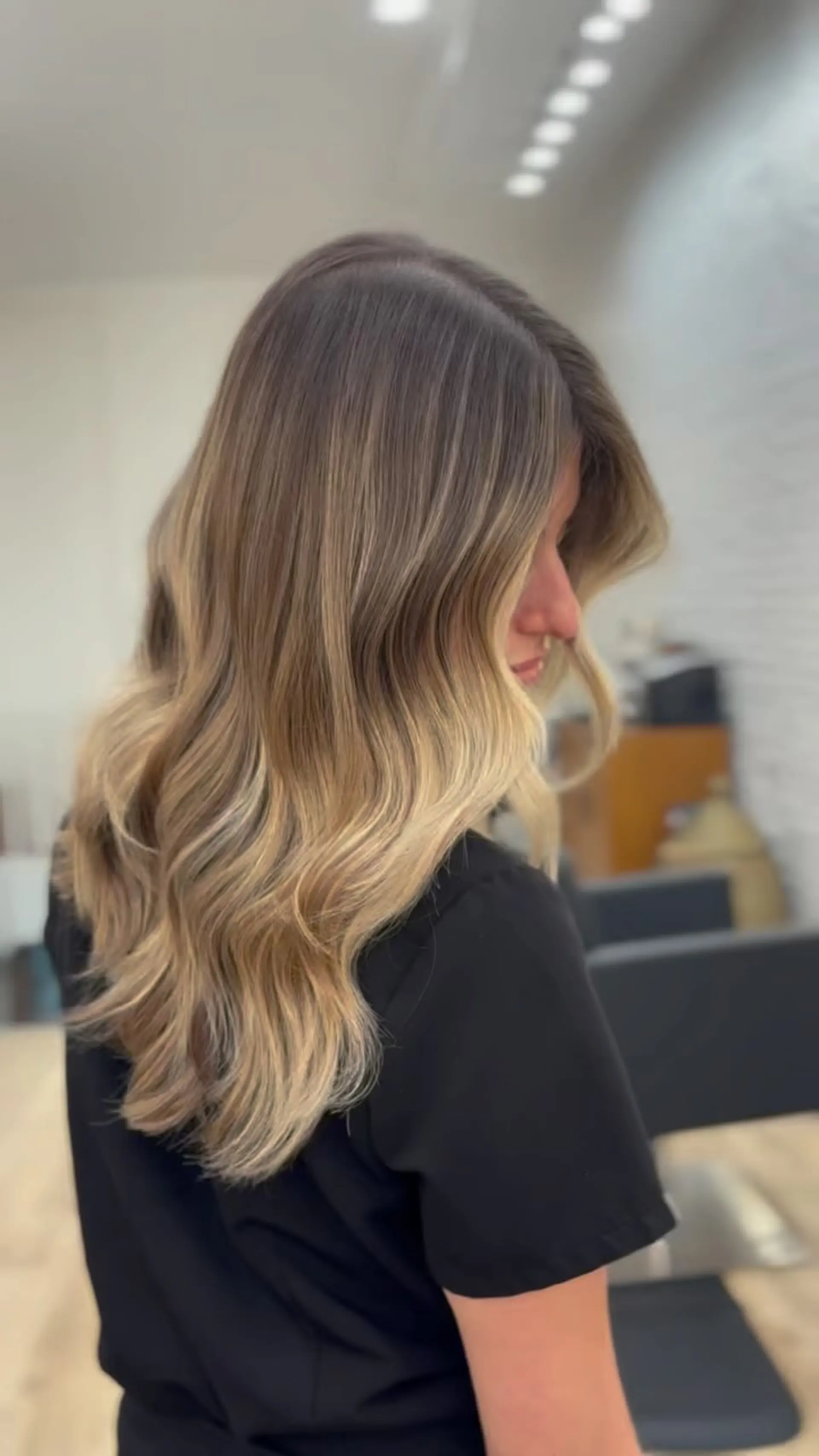 Long hair featuring a seamless balayage transition from light brown roots to warm golden blonde, styled in soft waves. 1