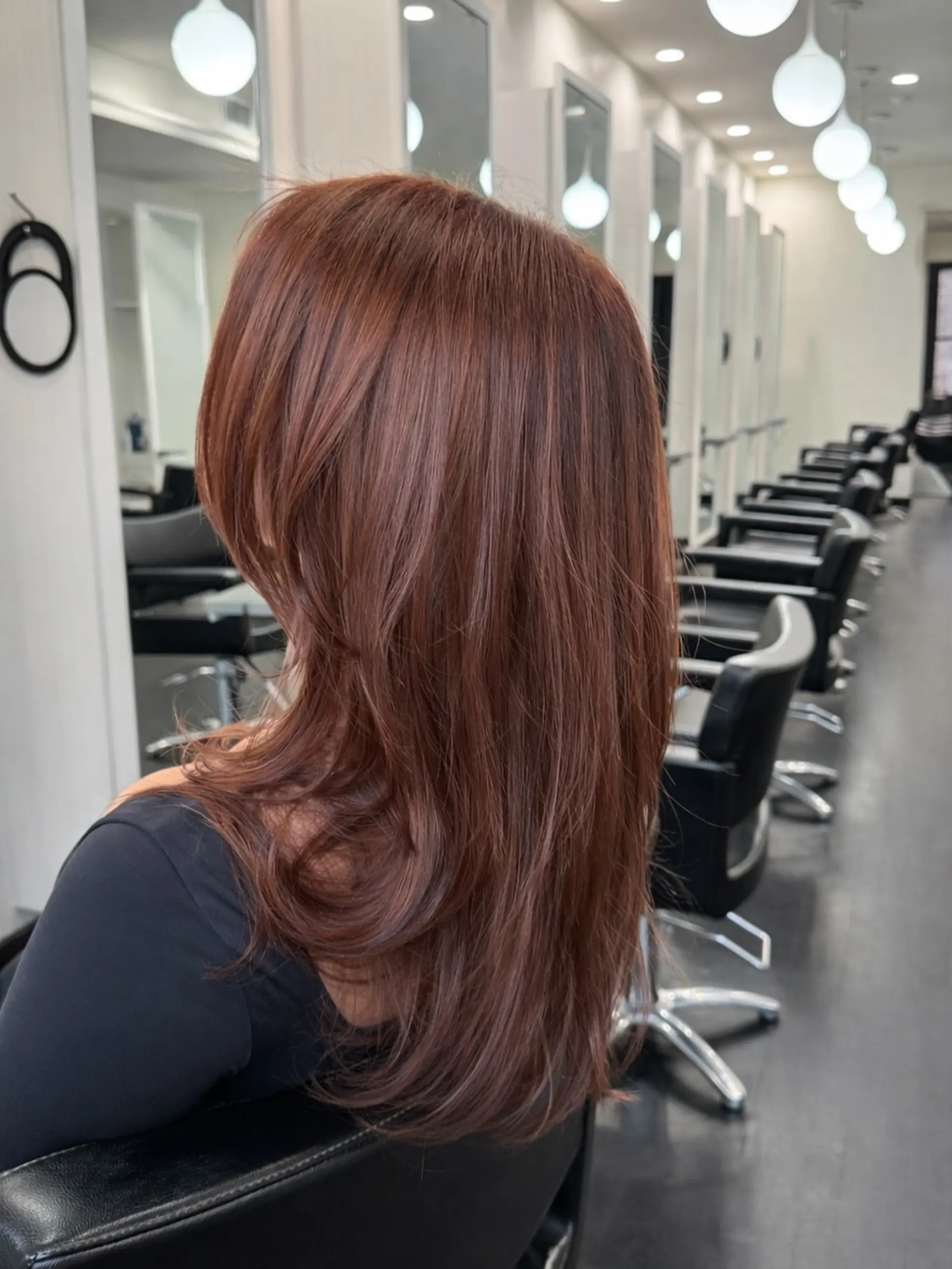 Rich cowboy copper long layered hair styled with a smooth, voluminous blowout and gently curved ends. 1