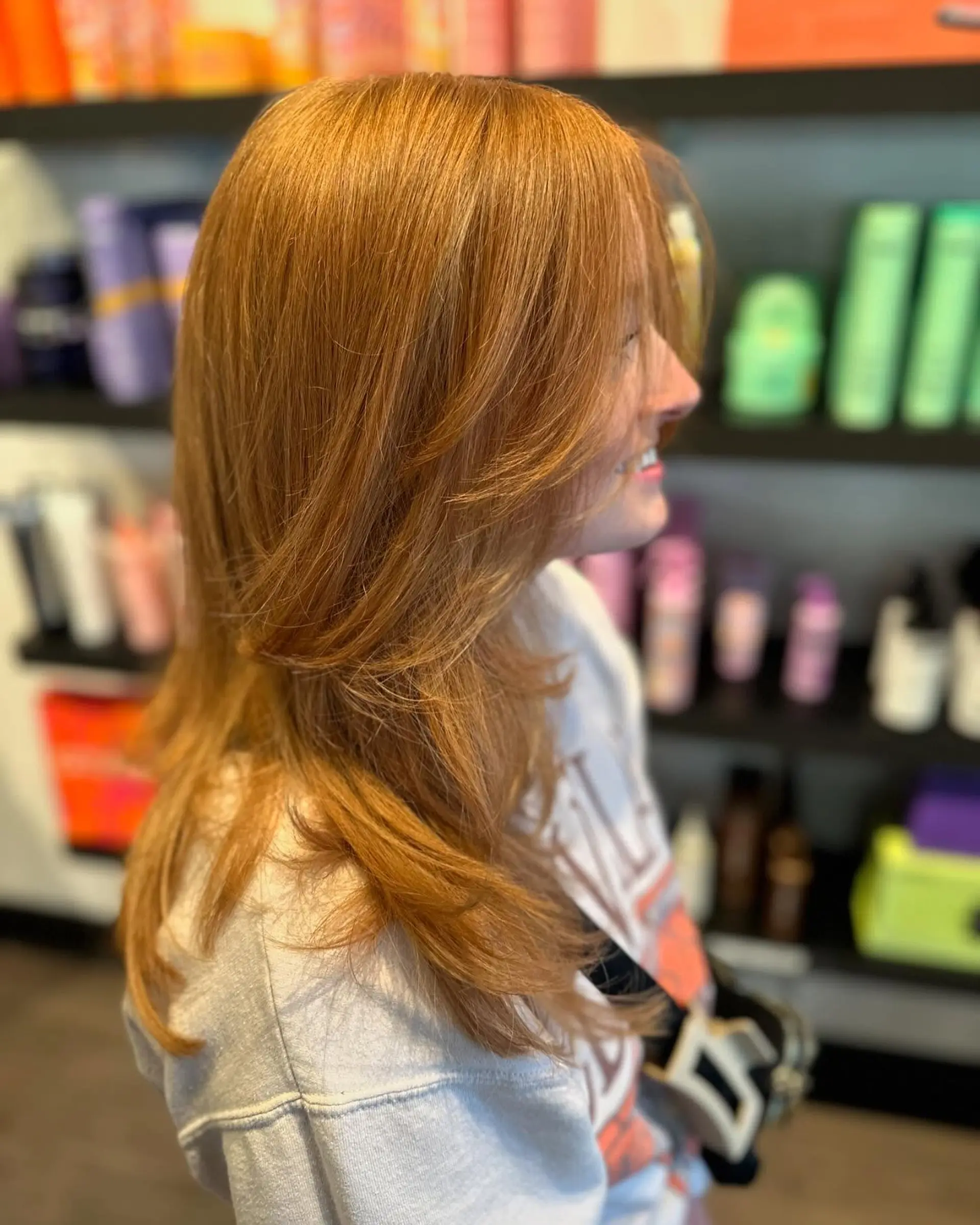 A textured butterfly cut featuring wispy face-framing layers and sweeping curtain bangs, styled with a soft blowout. 1