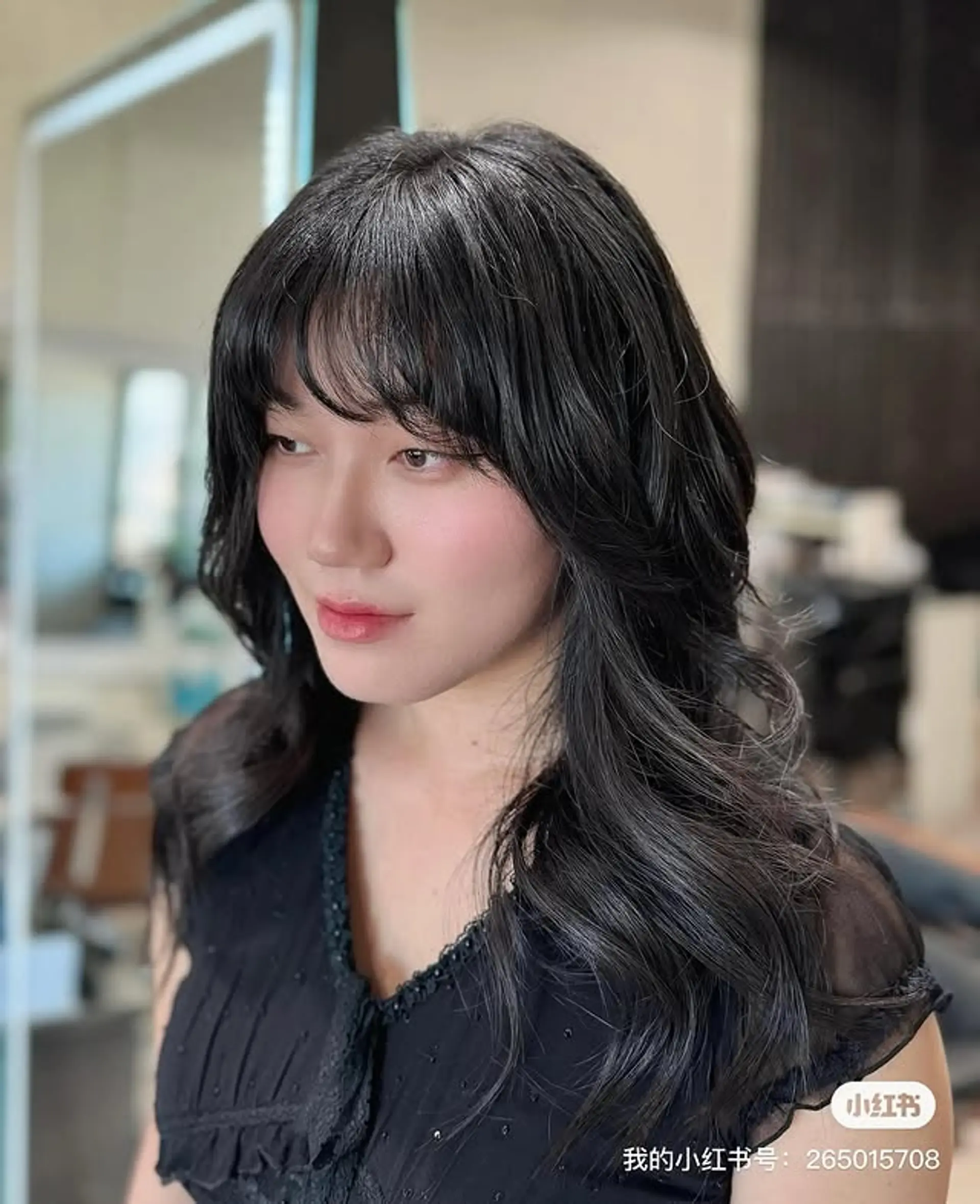 A long, layered cut characterized by soft, voluminous waves that cascade past the shoulders, complemented by delicate, wispy see-through bangs that gracefully frame the forehead. 1