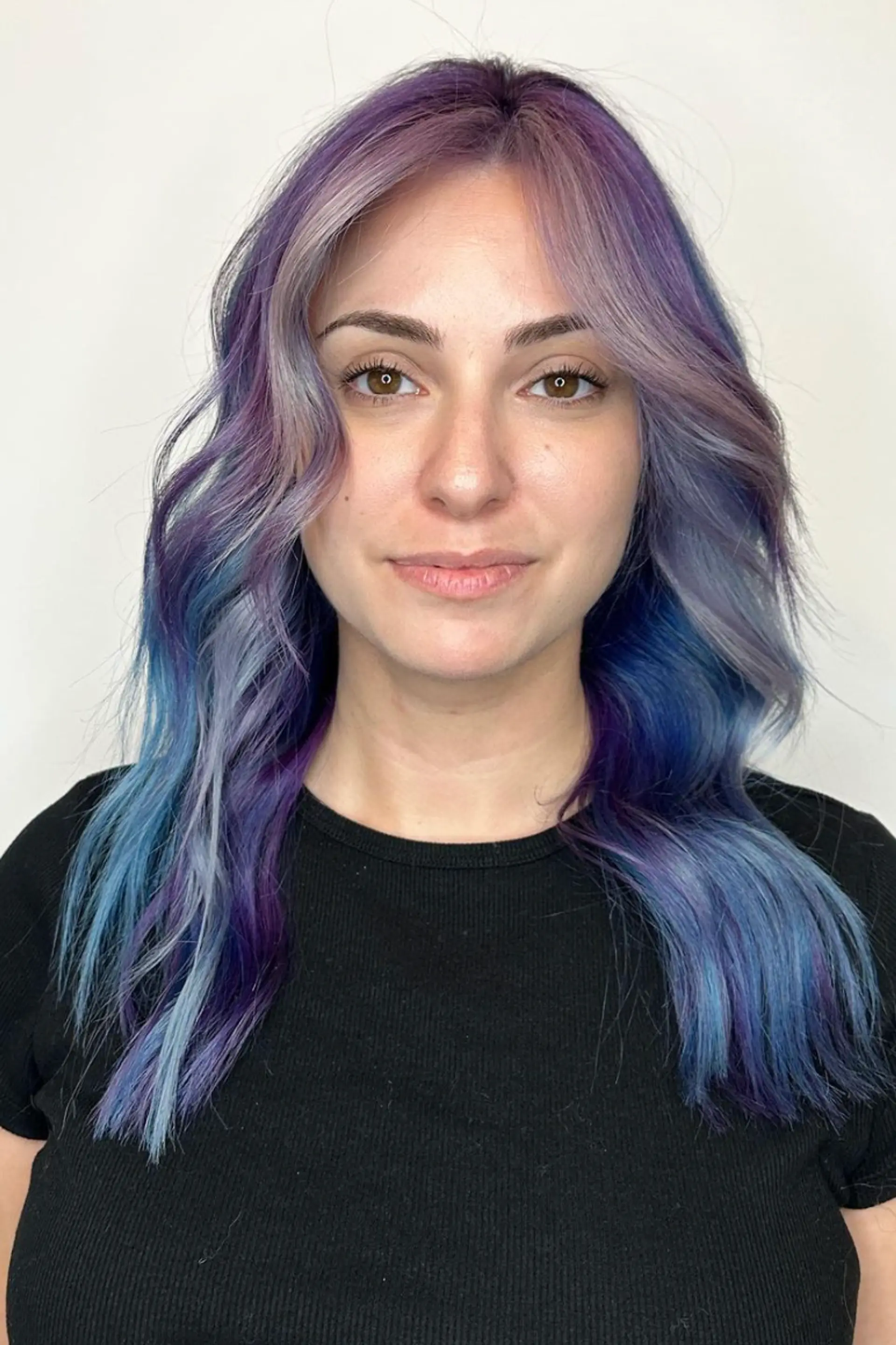 Medium-length wavy hair in lavender, purple, and blue tones with a center part and subtle waves.

Color by @simabeautynyc
 1