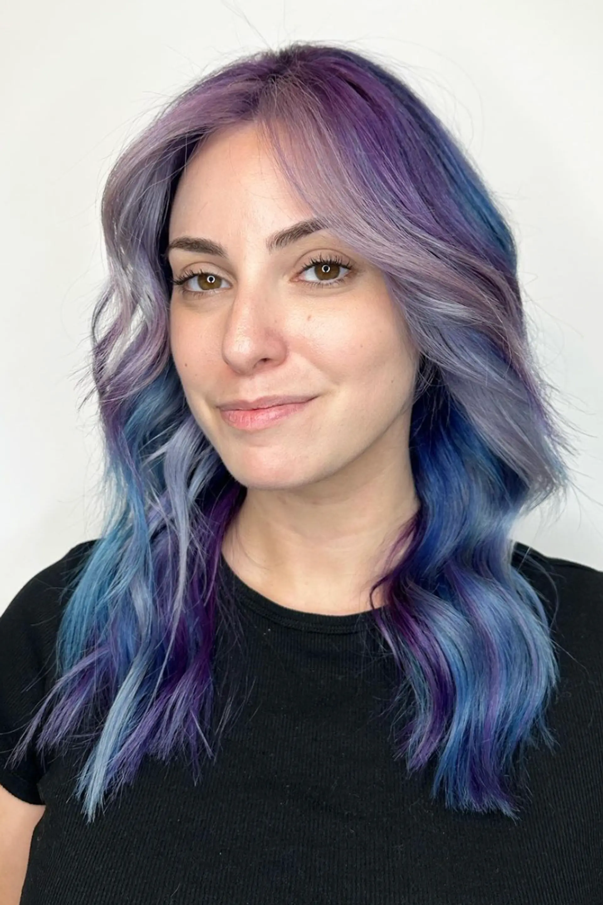 Medium-length wavy hair in lavender, purple, and blue tones with a center part and subtle waves.

Color by @simabeautynyc
 2