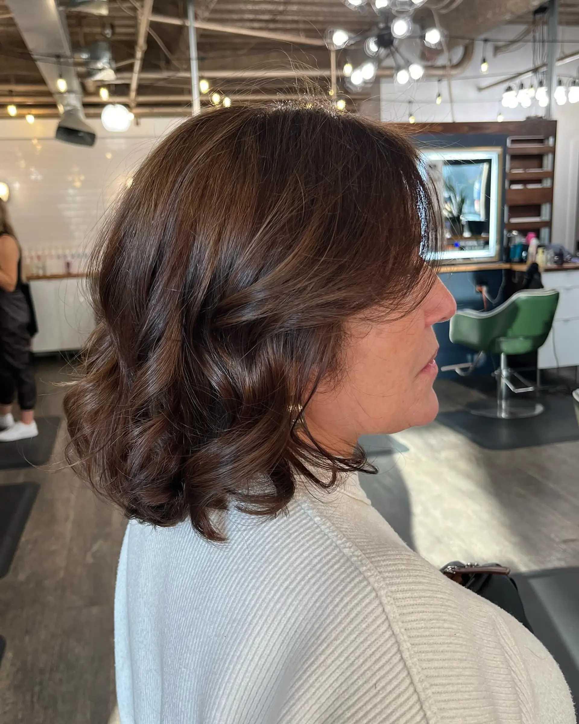 Shoulder-length rich brunette lob styled with soft waves and sweeping face-framing fringe. 1