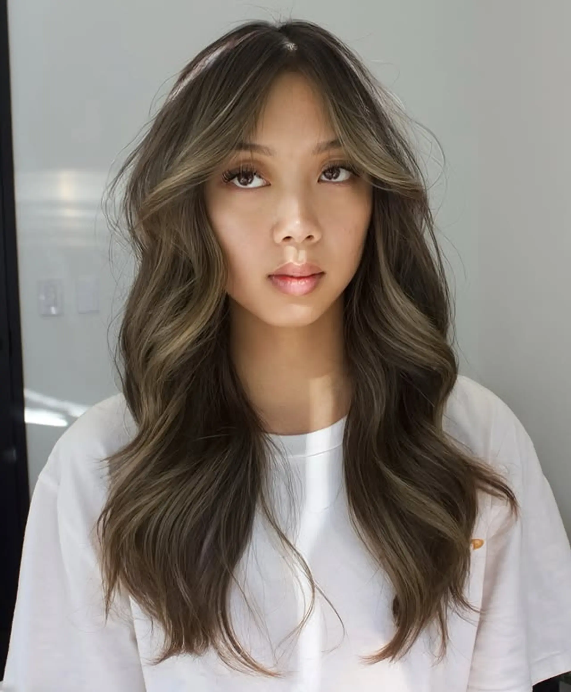 Long, wavy ash brown hair with blonde balayage and curtain bangs. 1
