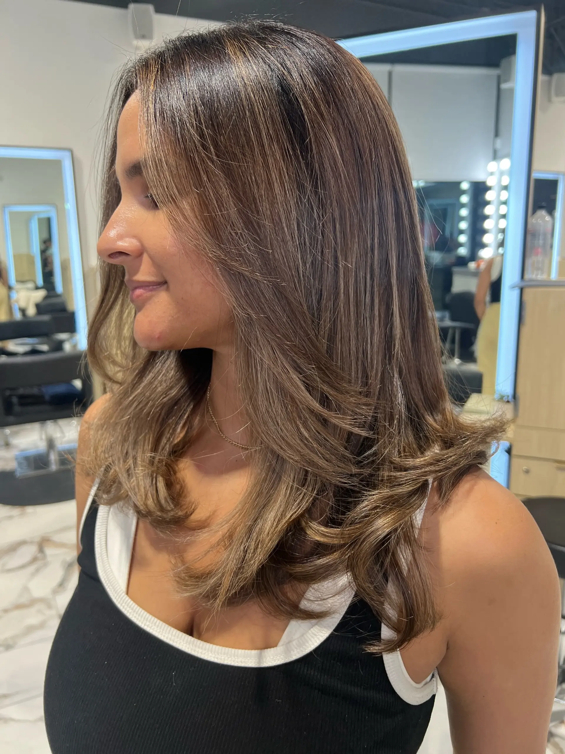 Long dimensional brunette hair with soft, layered framing and flipped-under ends styled in a smooth blowout. 1