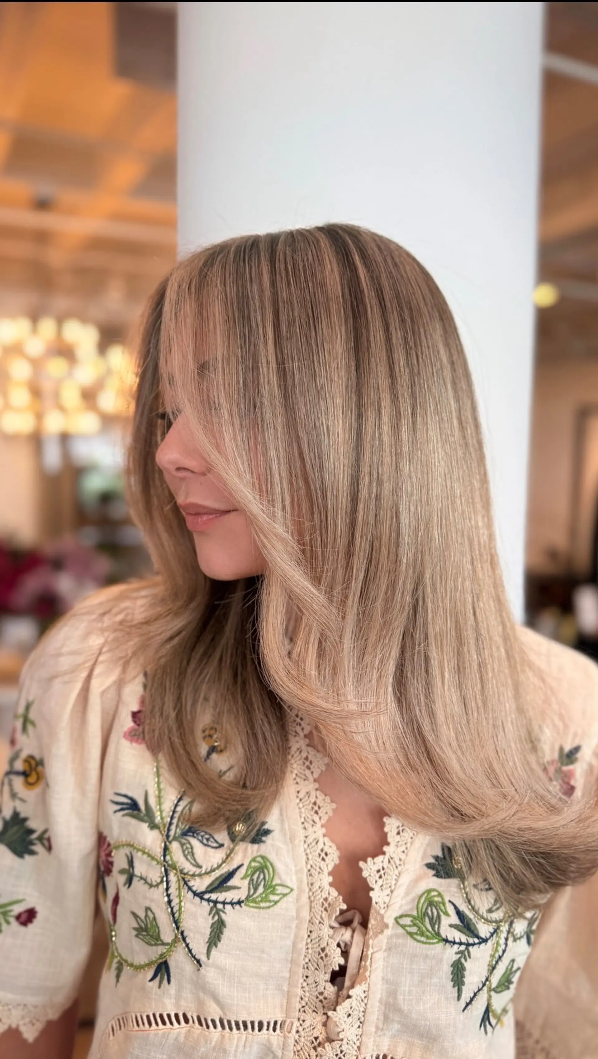 Long creamy beige blonde hair styled with soft, face-framing curtain bangs and a smooth curved blowout. 1