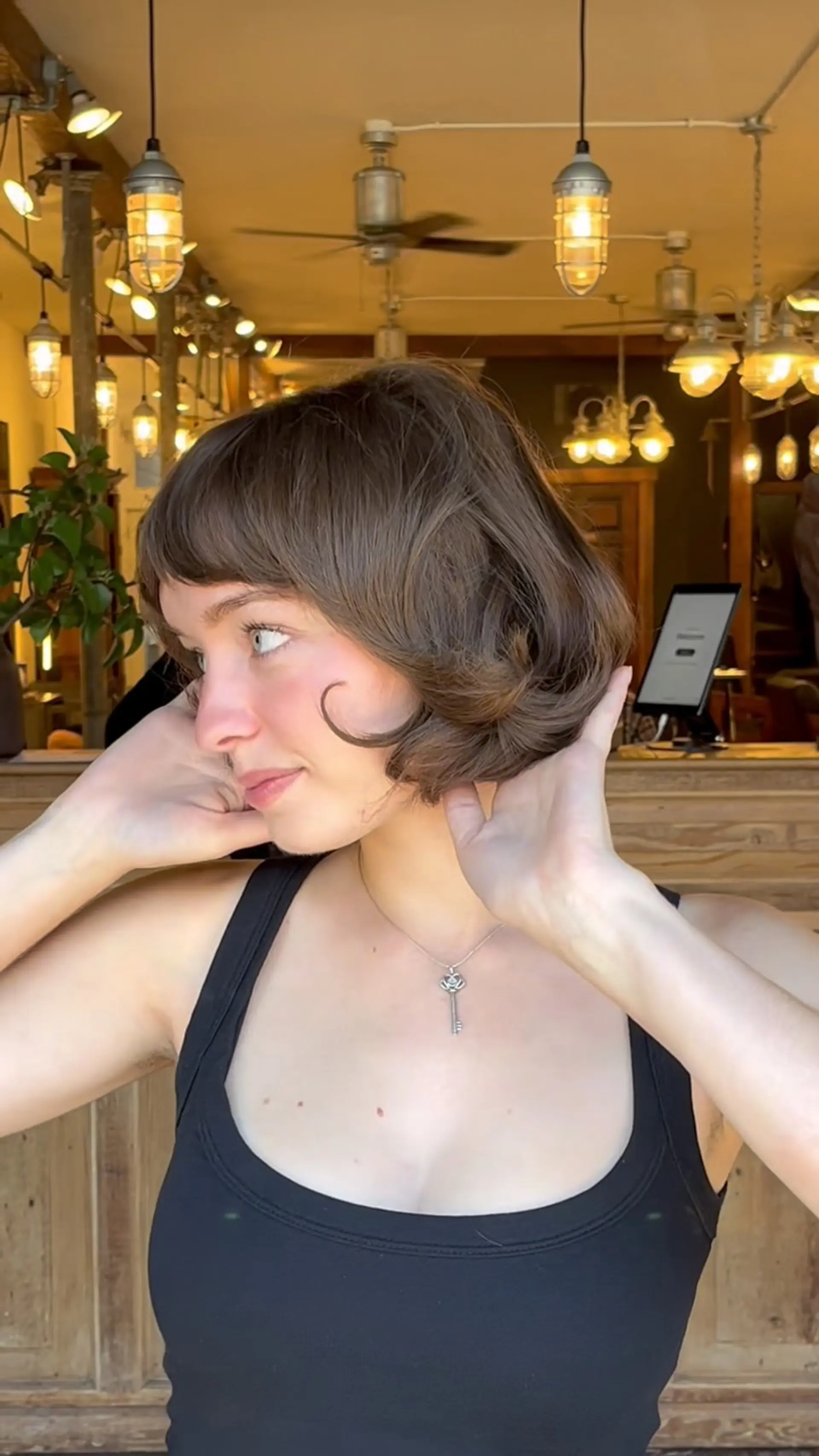 A retro-inspired chin-length brunette bob styled with curled flipped ends and textured micro bangs. 1
