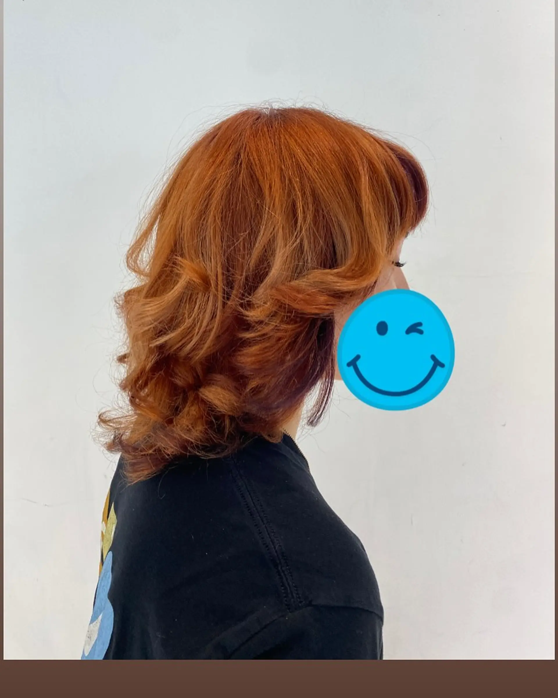 Medium-length vibrant copper haircut with textured layers, flipped ends, and face-framing curtain bangs. 1