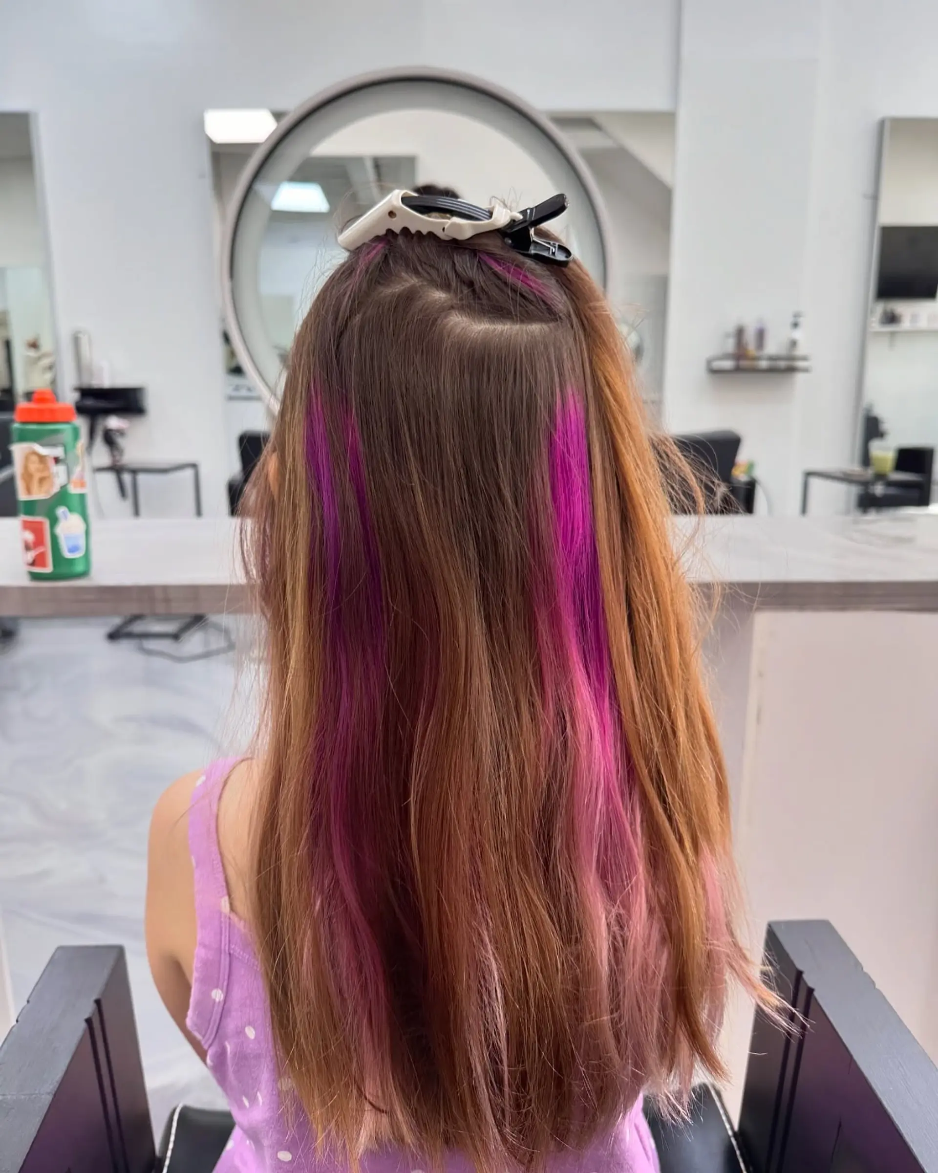 Long straight brown hair clipped up at the crown to showcase vibrant peekaboo magenta and pink highlights. 1