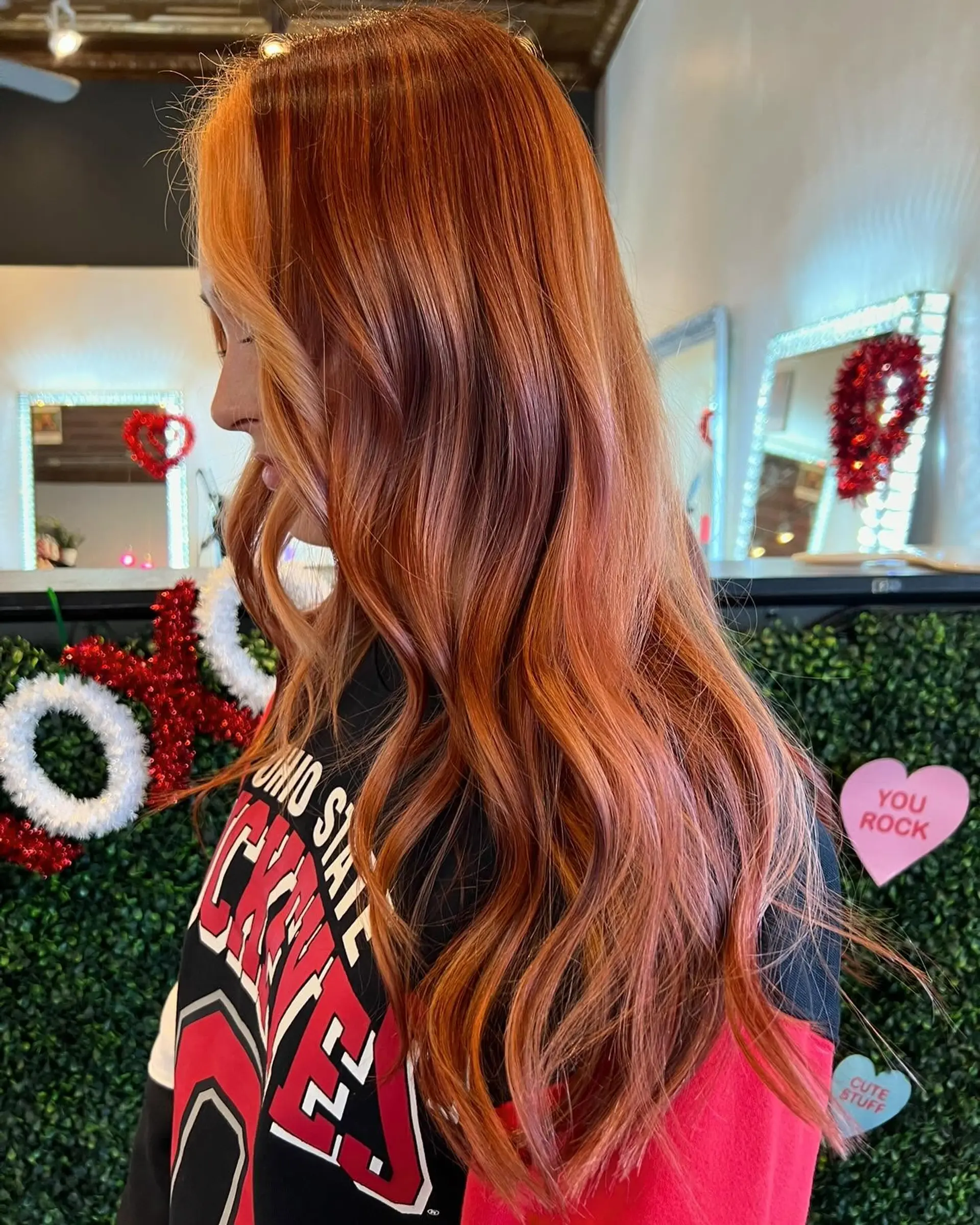 Side view of long, multidimensional vibrant copper hair styled with soft, loose waves. 1