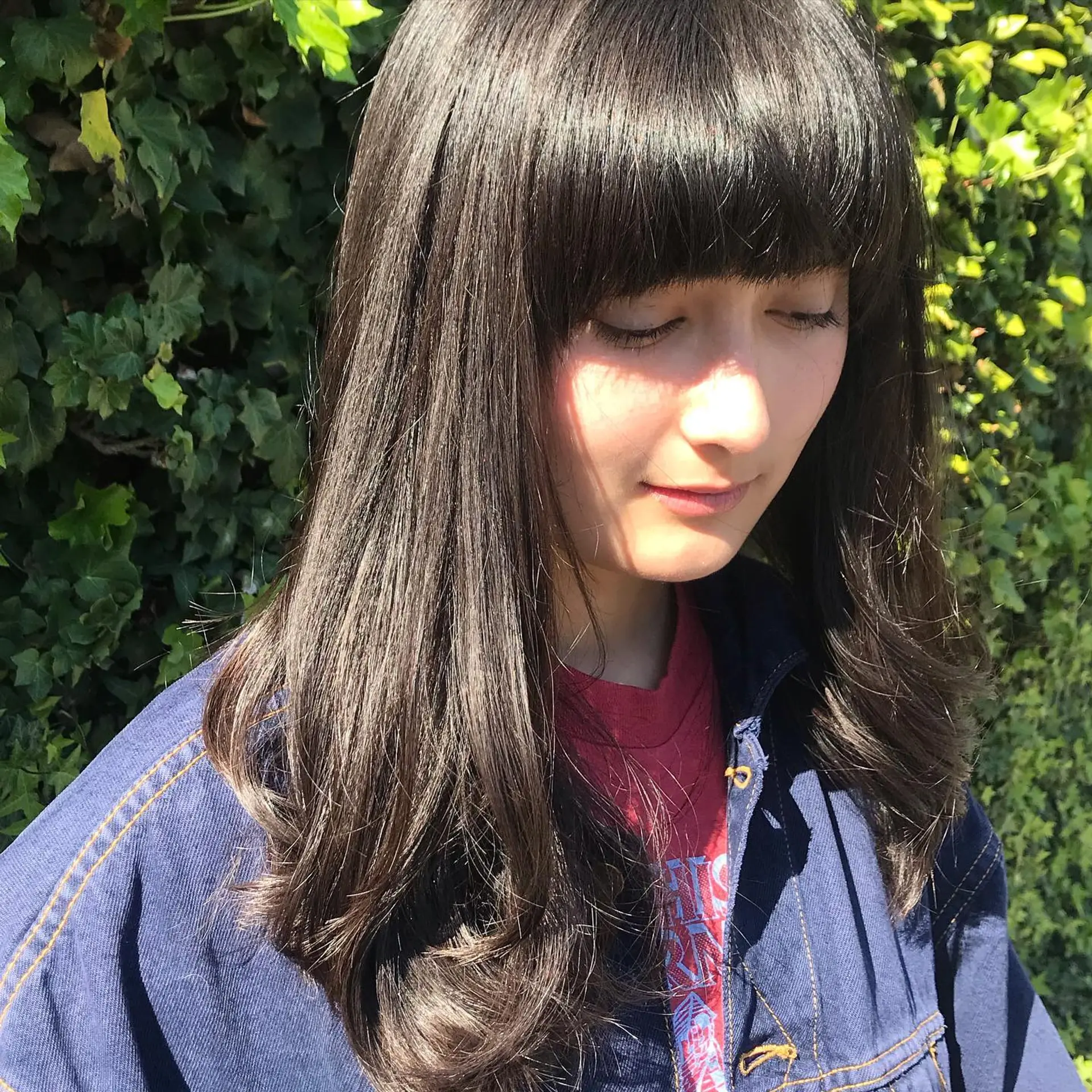Long layered dark brunette hair styled smooth with a full eyebrow-length fringe and softly curved ends. 1