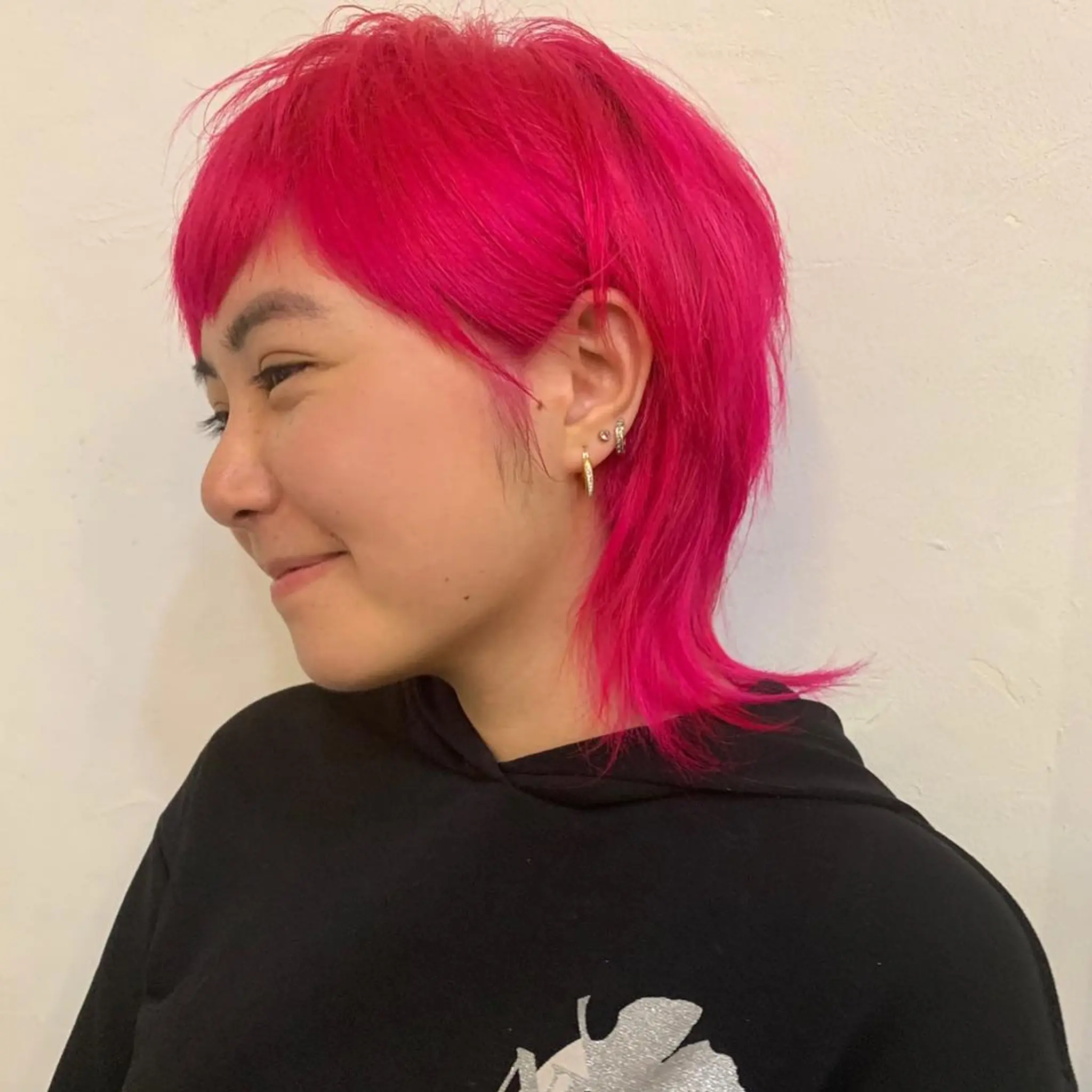 The hairstyle is a vibrant magenta, medium-length cut featuring straight hair with layers. It combines elements of a pixie and mullet style, with shorter choppy layers on top and longer, straighter locks at the back. The front has a short, blunt fringe that frames the face by Zen. 2