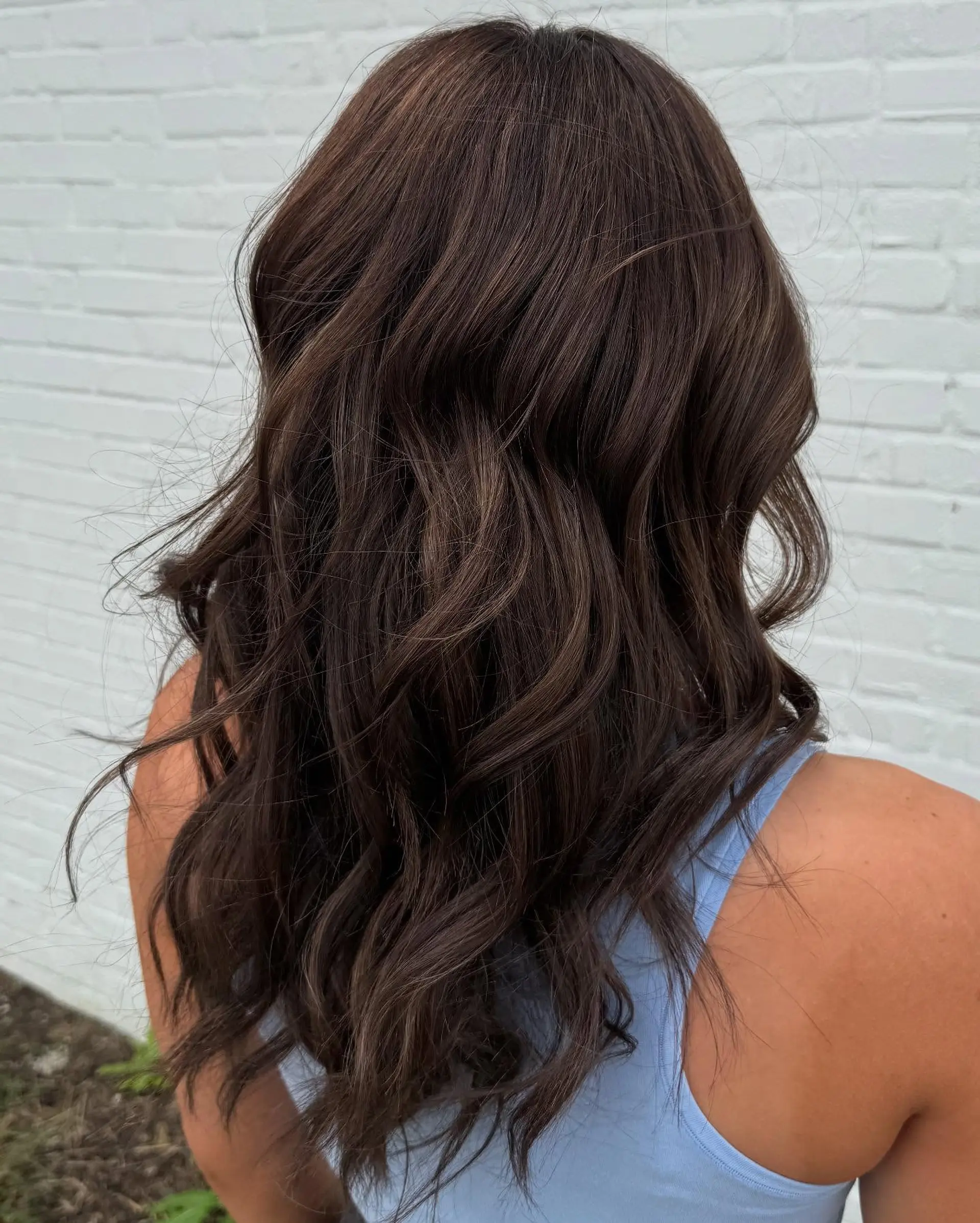 Rich chocolate brown hair styled into textured, loose waves with subtle dimensional undertones. 1