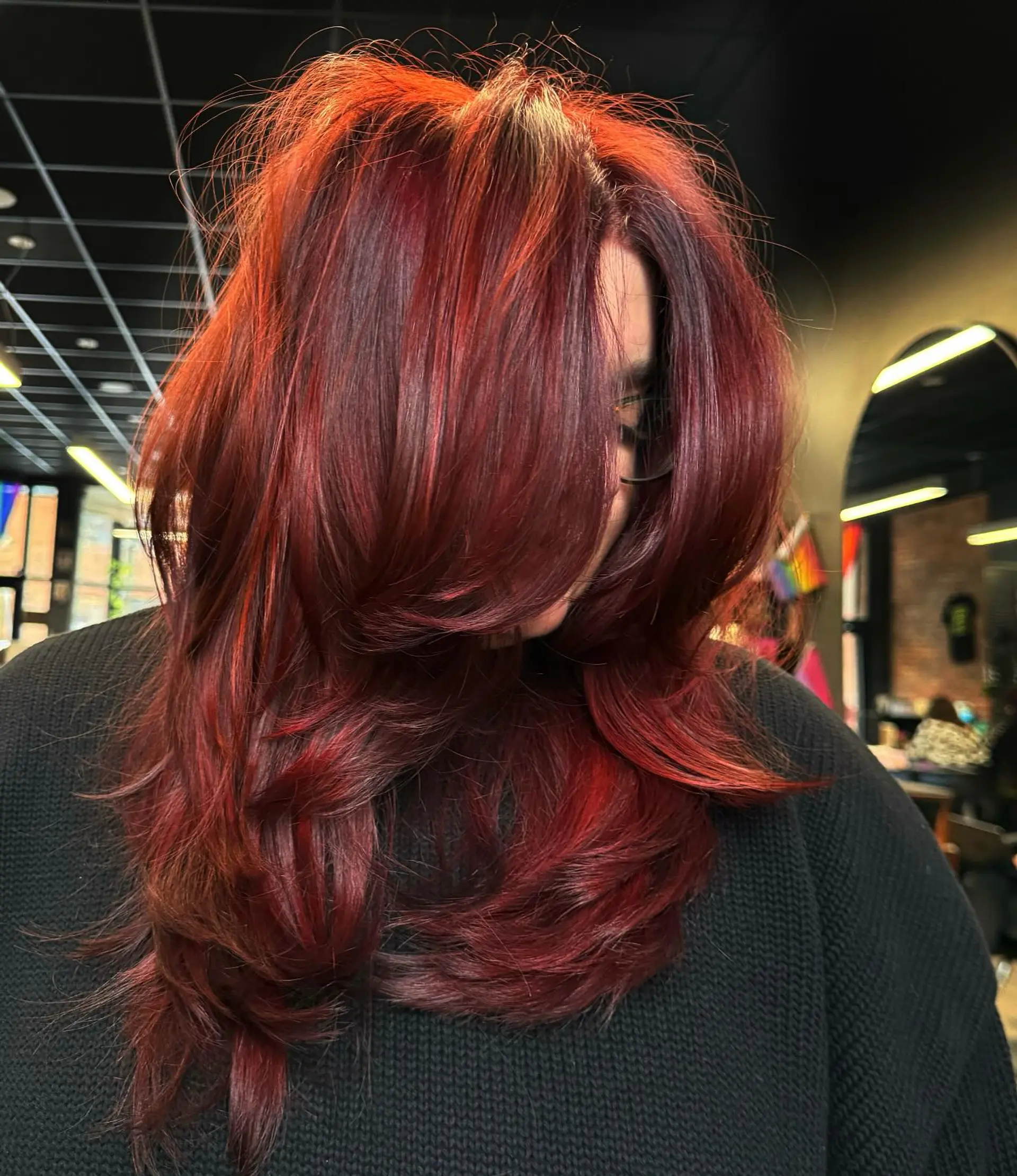 Vibrant, deep cherry red hair styled with voluminous face-framing layers and a bouncy blowout. 1