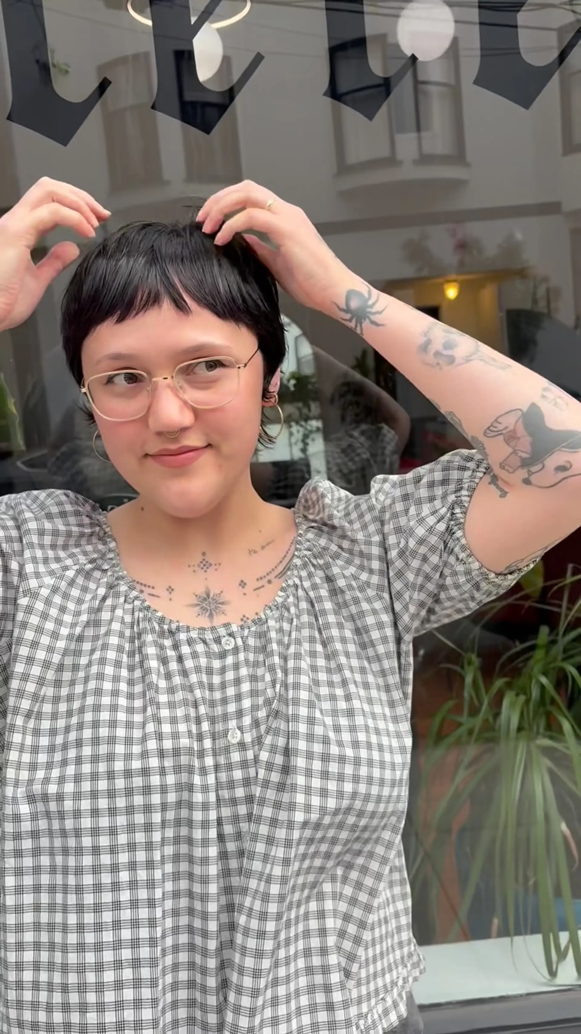 A short, textured dark pixie cut featuring piecey micro bangs across the forehead. 1