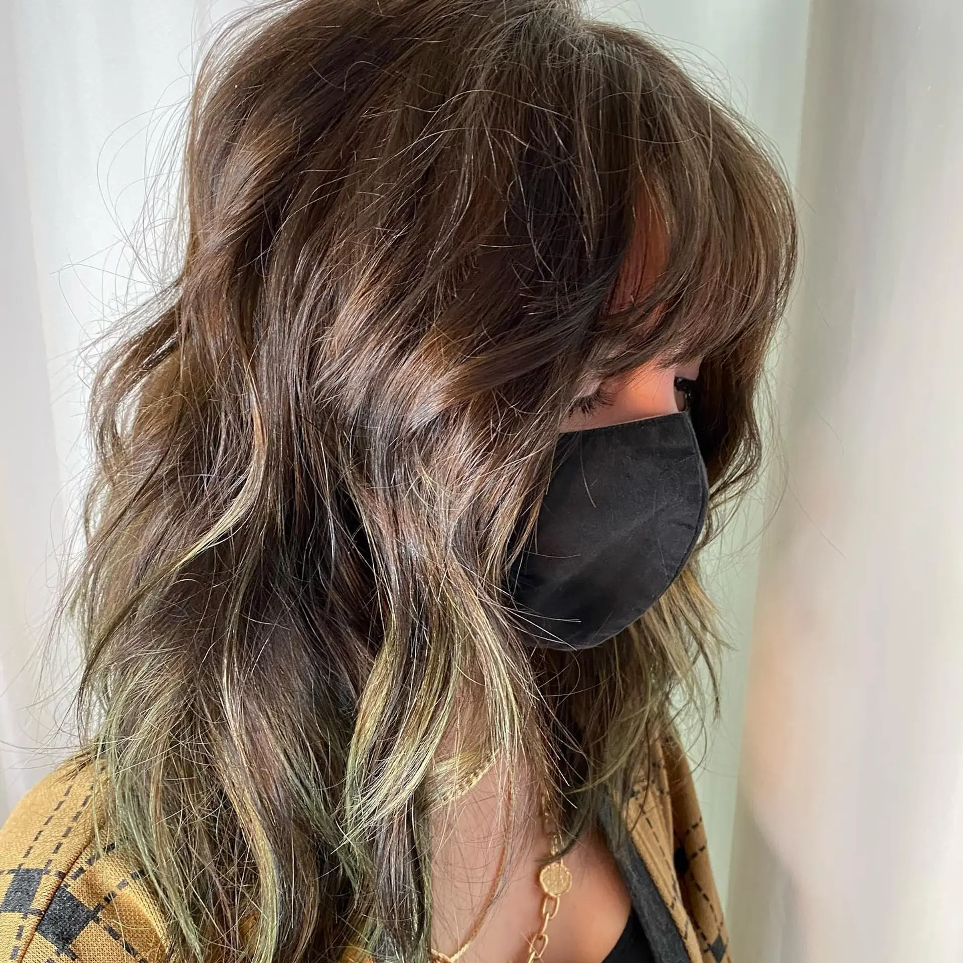 A medium-length wavy lob featuring a deep dark brown shadow root that seamlessly blends into striking moss green ends. 2