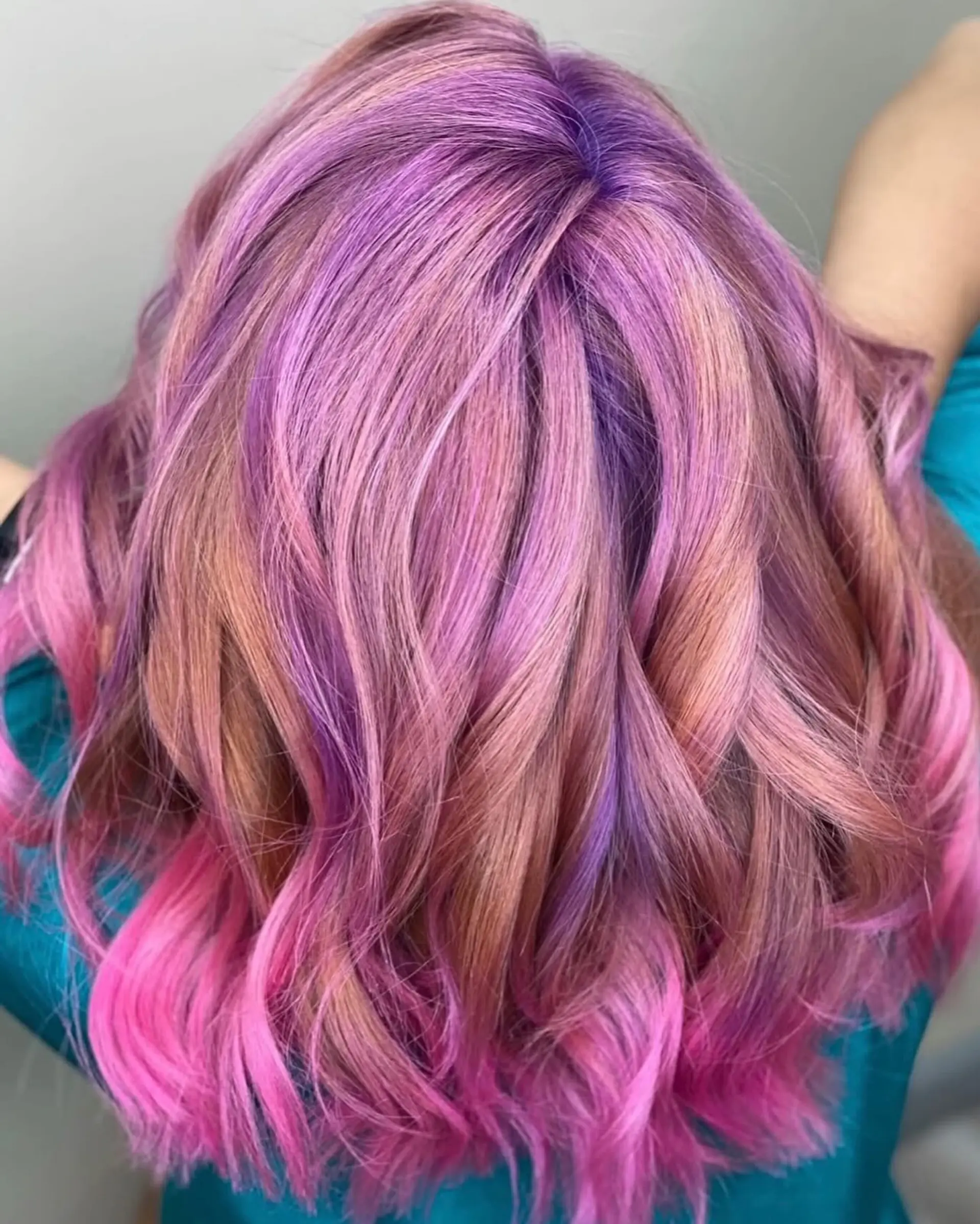 A medium-length dimensional hairstyle featuring a vibrant mix of purple, magenta, and rose-pink tones styled in soft waves. 1