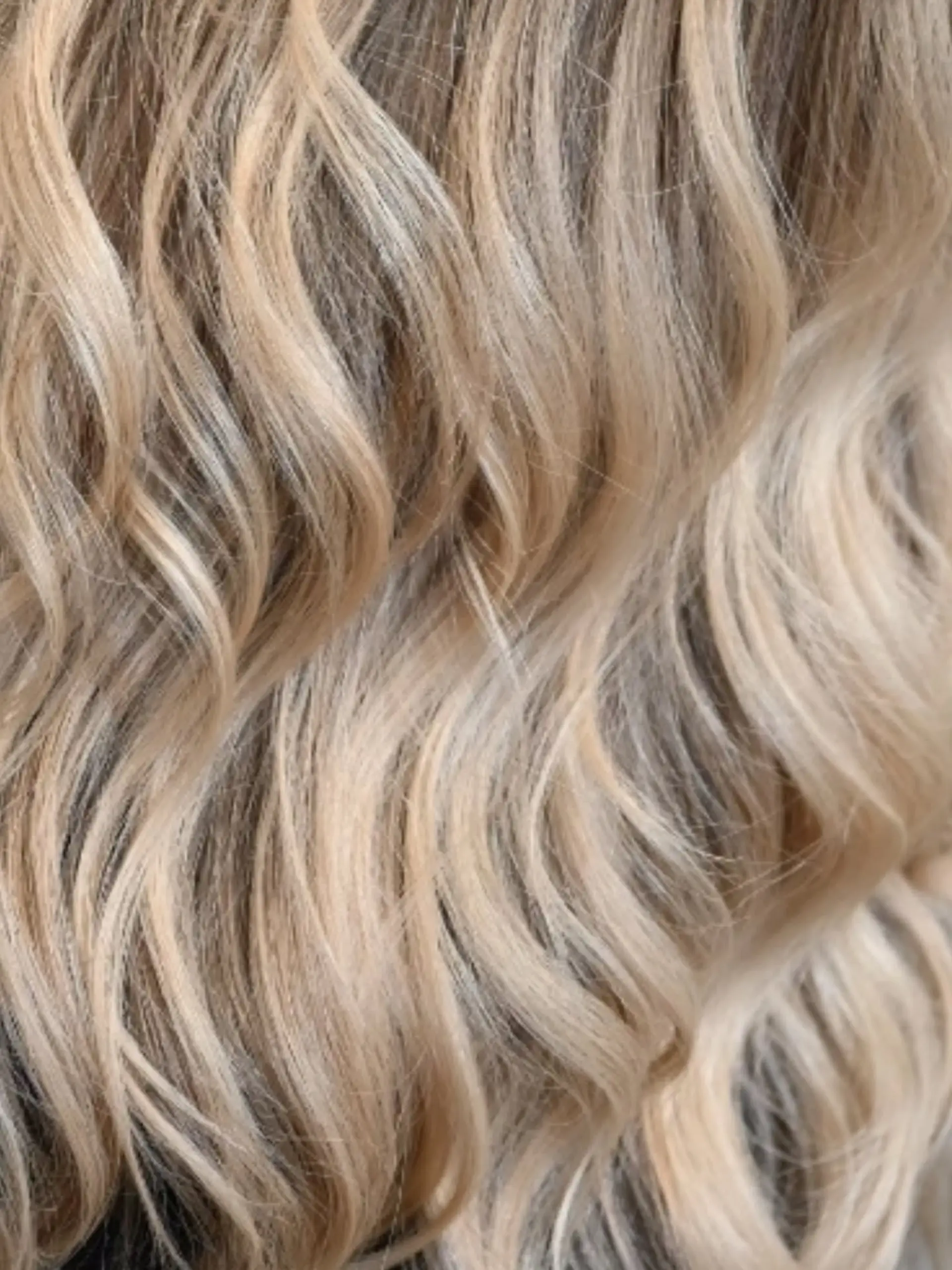 Softly waved hair featuring a dimensional mix of bright blonde highlights and natural lowlights. 1