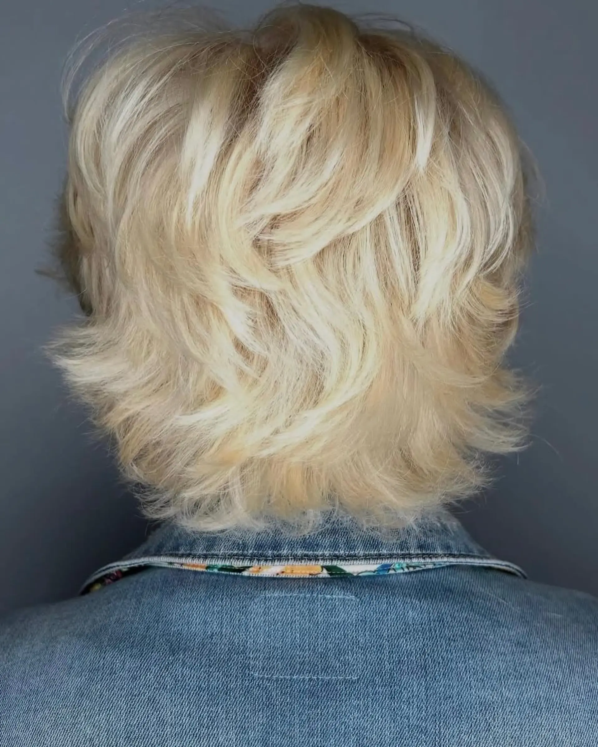 A textured, layered short blonde shag with feathered, flicked-out ends viewed from behind. 1