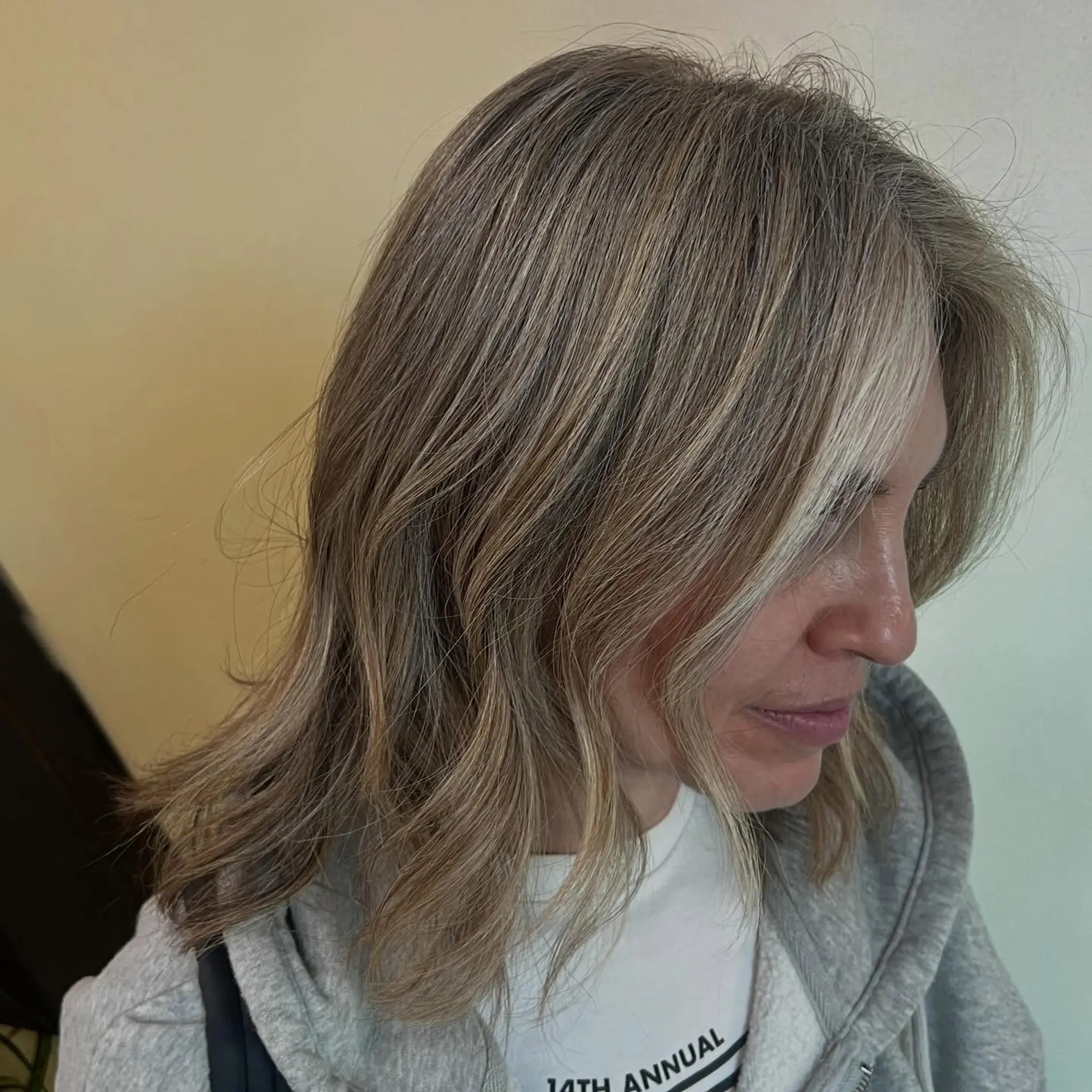 A collarbone-grazing lob with soft waves, featuring seamless ash blonde highlights tailored for natural gray blending. 1