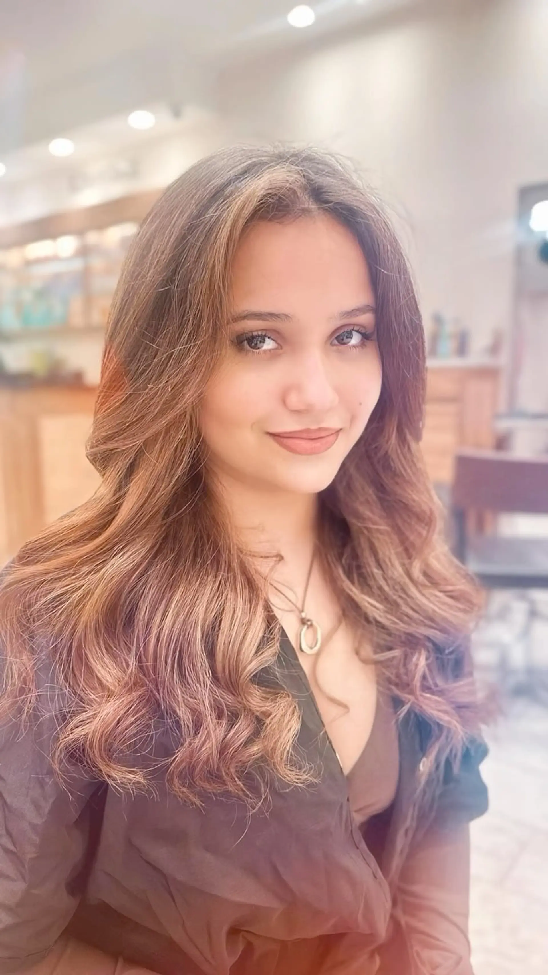 Long dimensional caramel balayage styled in loose, voluminous waves with face-framing layers. 1