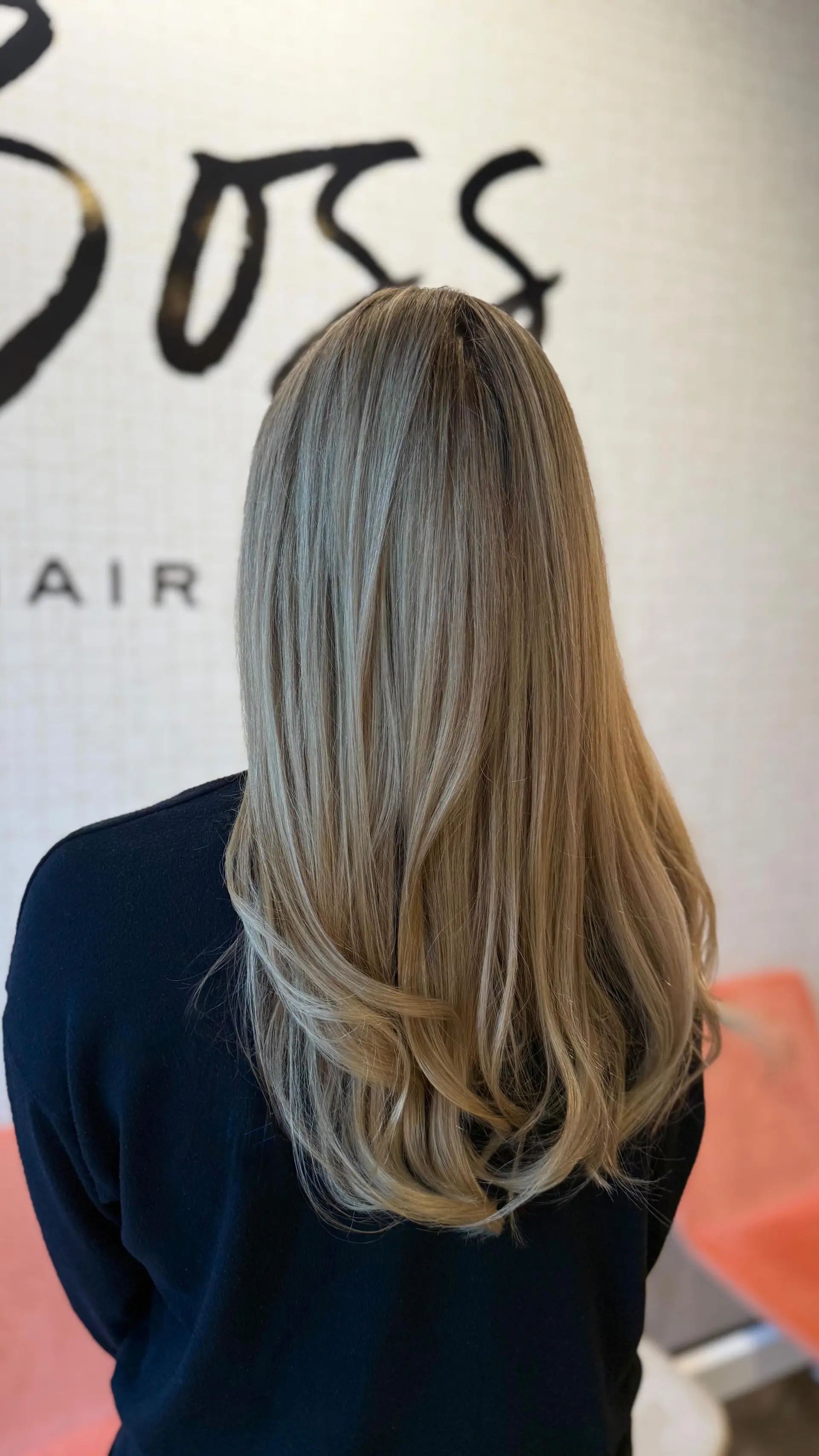 Long ash blonde highlighted hair styled into a smooth blowout with softly curled ends. 1