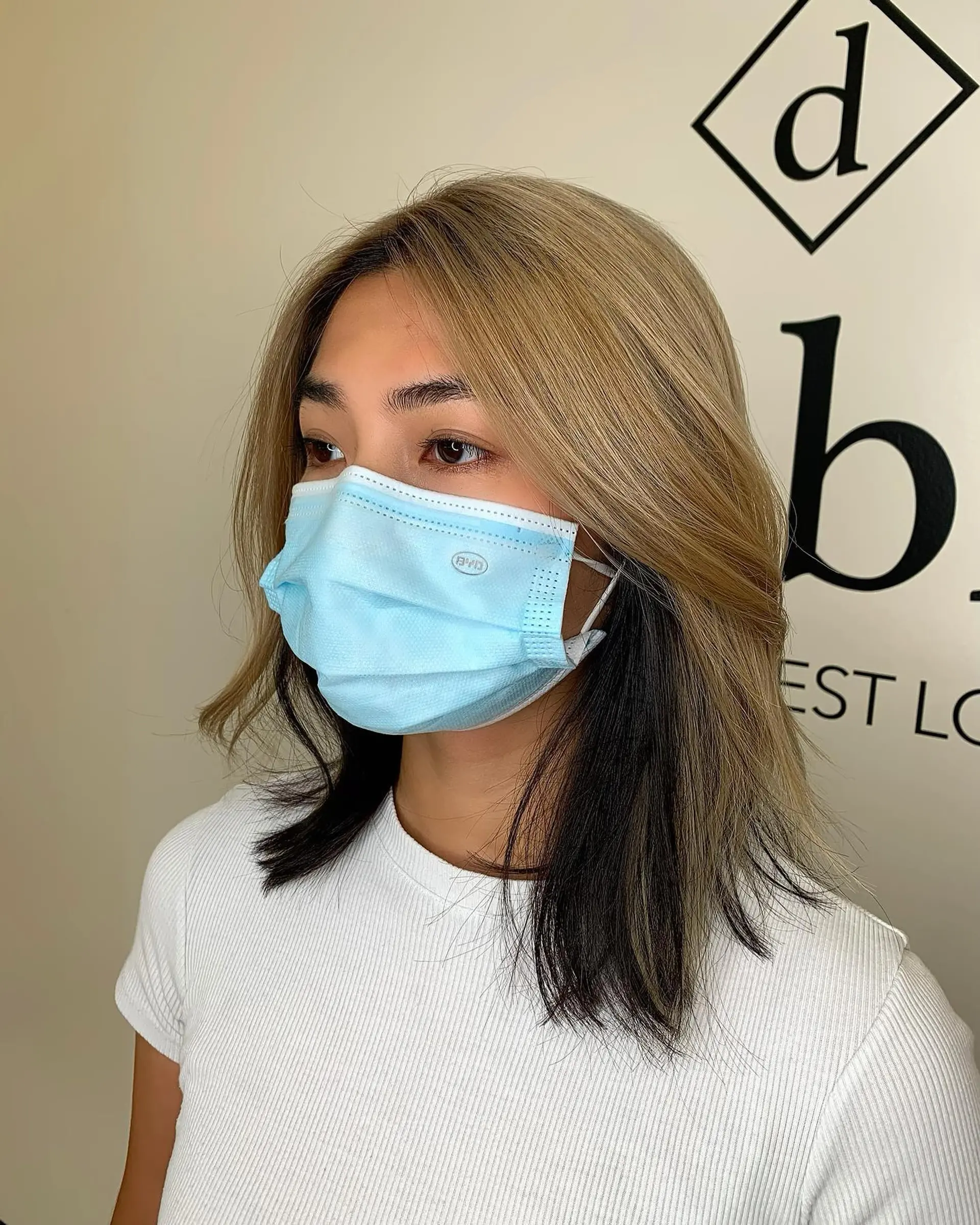 A medium-length lob featuring high-contrast two-tone coloring with an ash blonde top layer over jet-black underlayers, finished with soft face-framing layers. 1